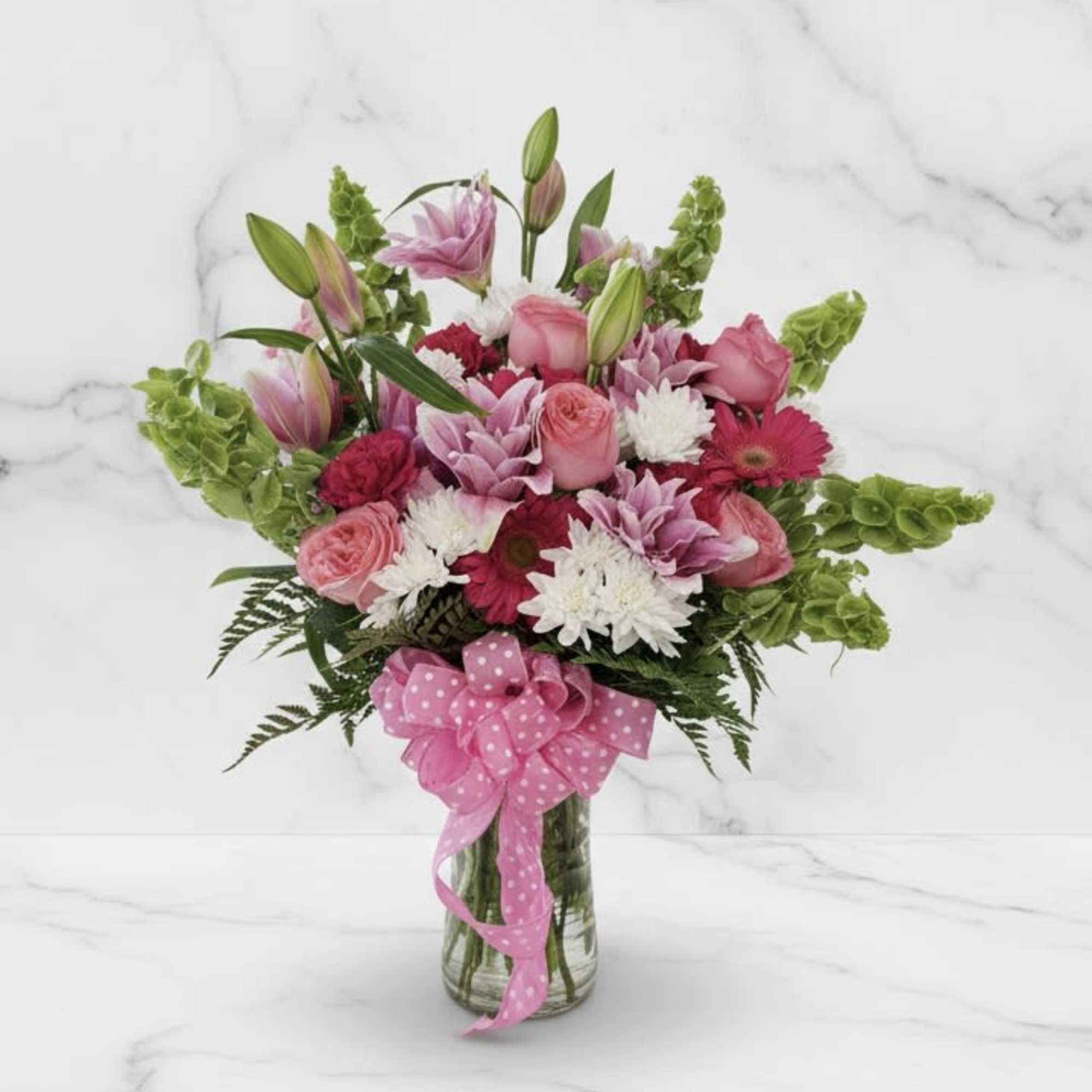 Pink lilies, roses, gerbera, carnations and white daisies in a clear vase