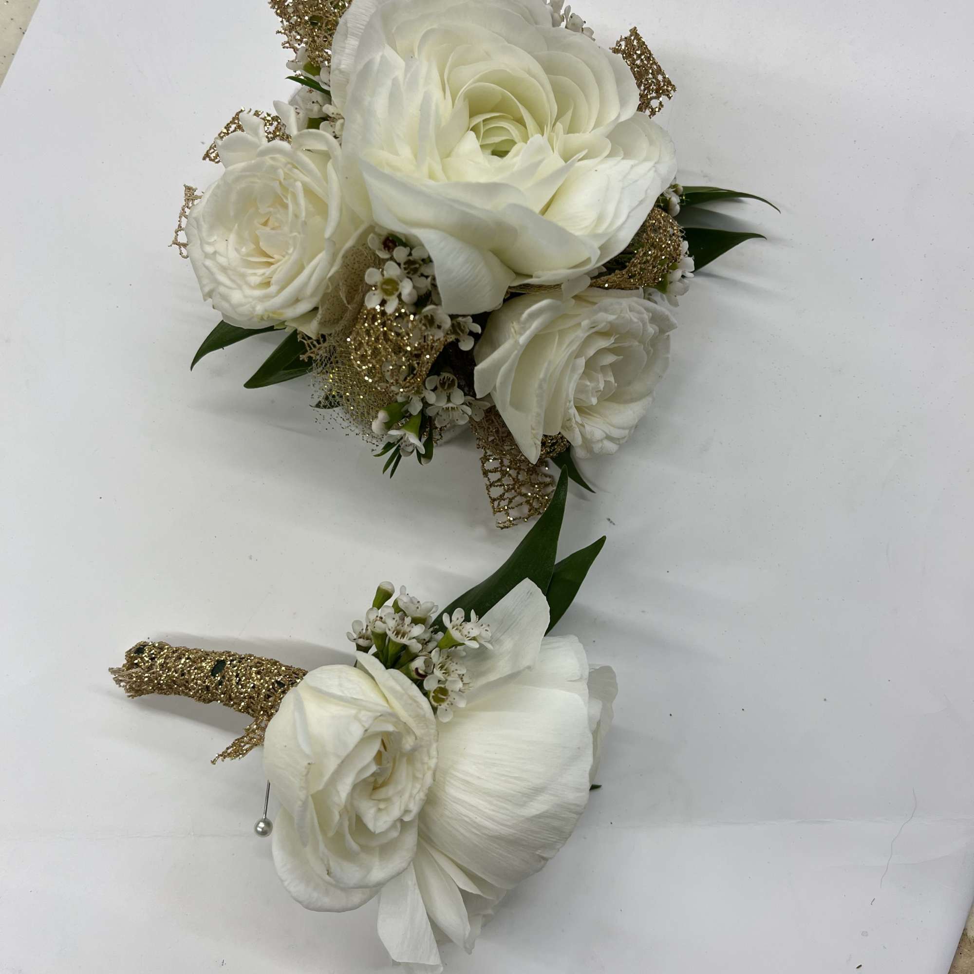 White rose corsage and matching boutonniere accented with small white blooms and gold ribbon.