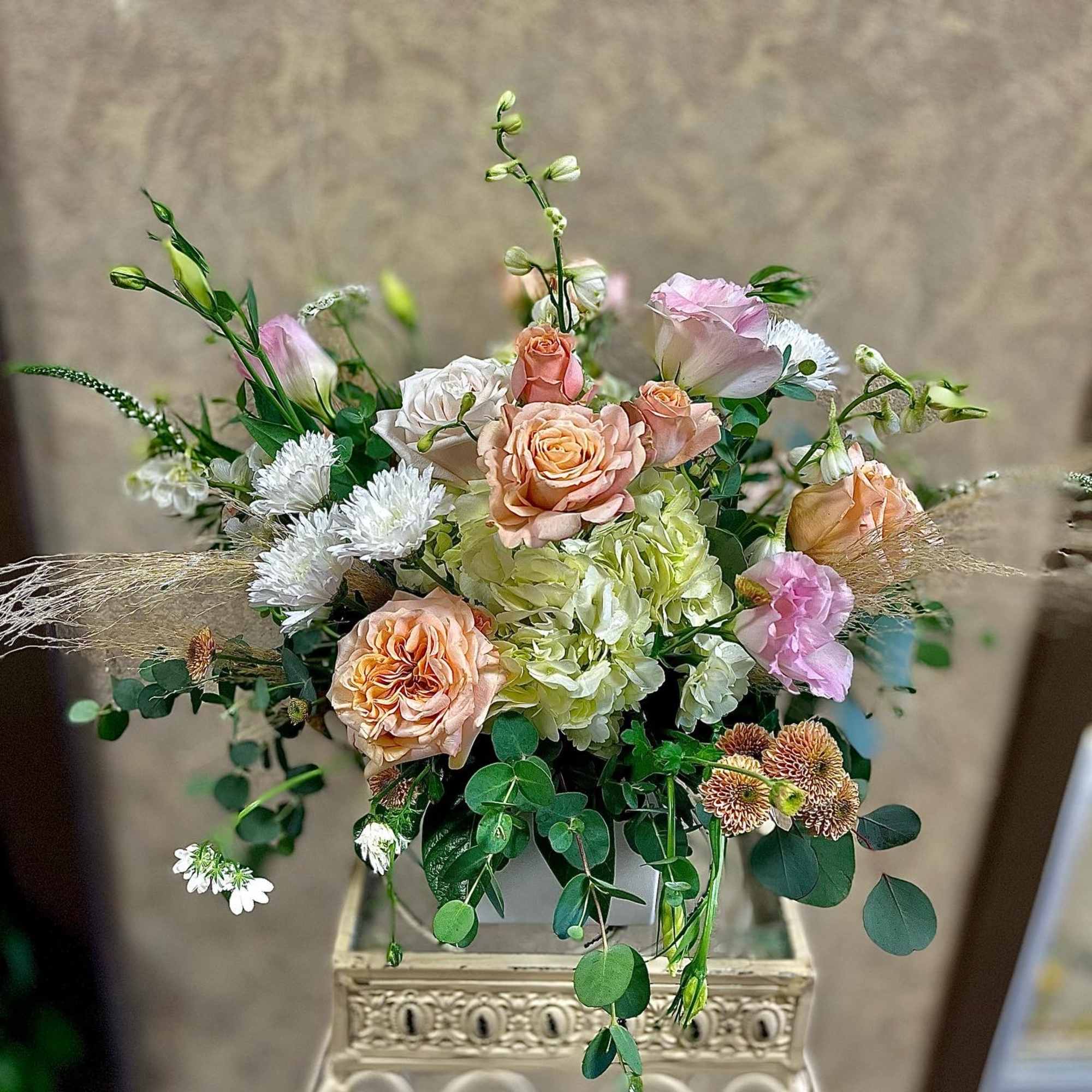 Peach roses and pale hydrangeas in a low arrangement with white blooms