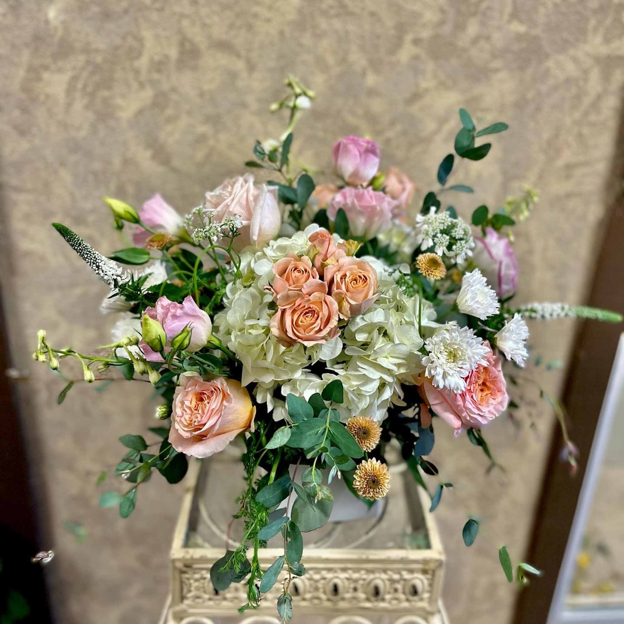 Blush roses and white hydrangeas arranged in a decorative vase