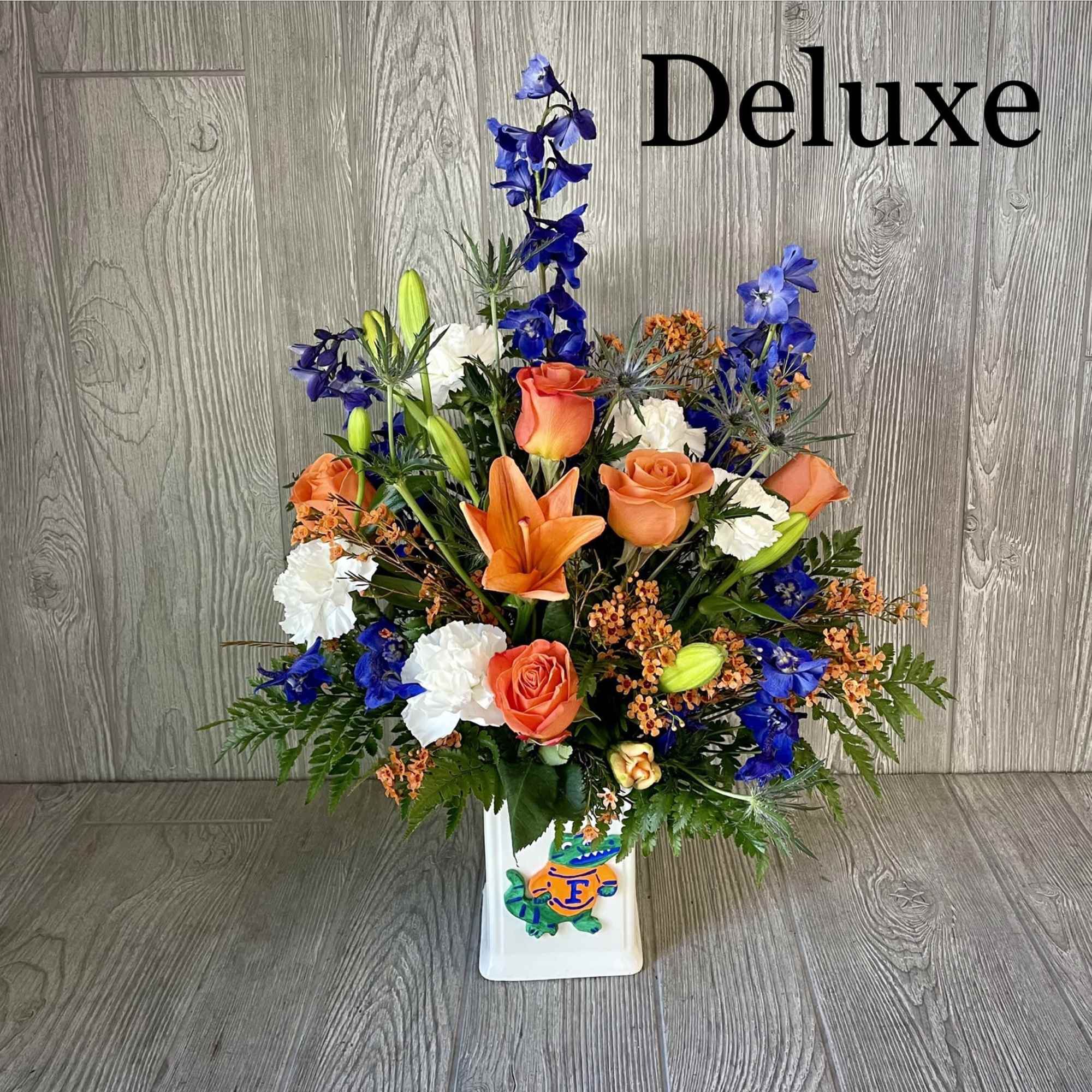 Orange and blue floral arrangement in a white vase
