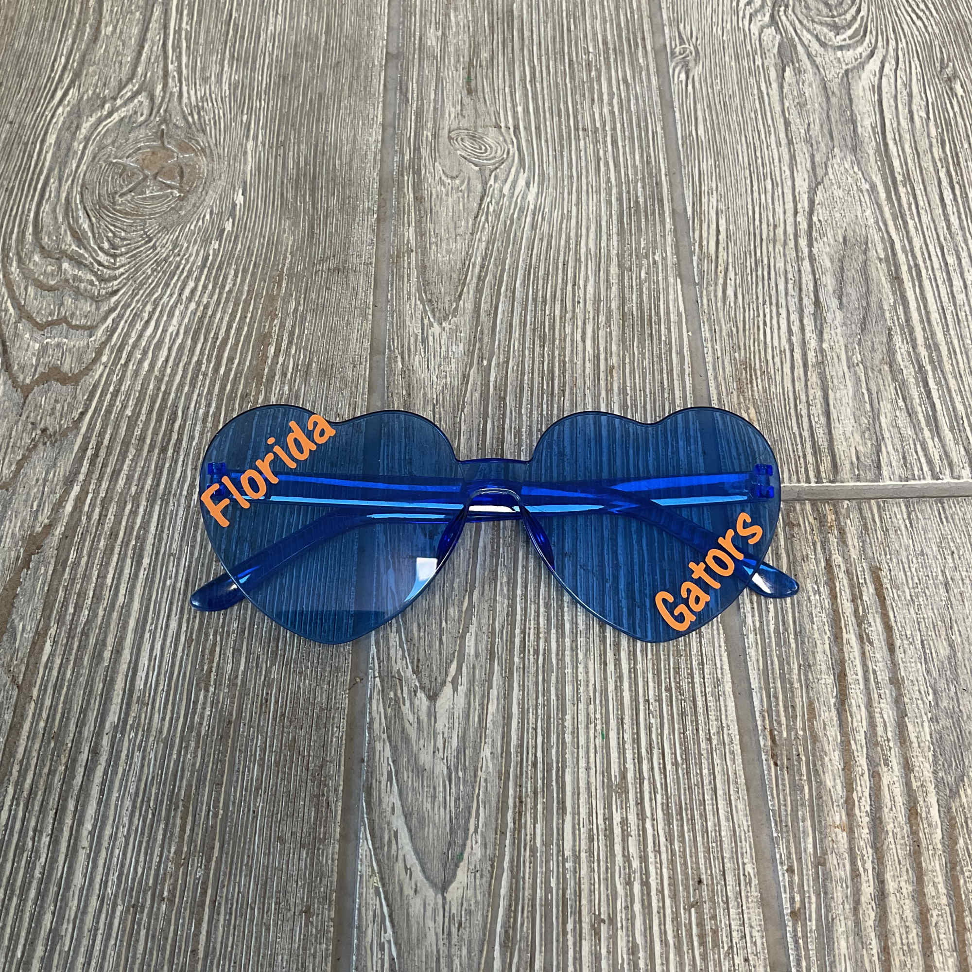 Blue heart-shaped sunglasses with orange text on the lenses