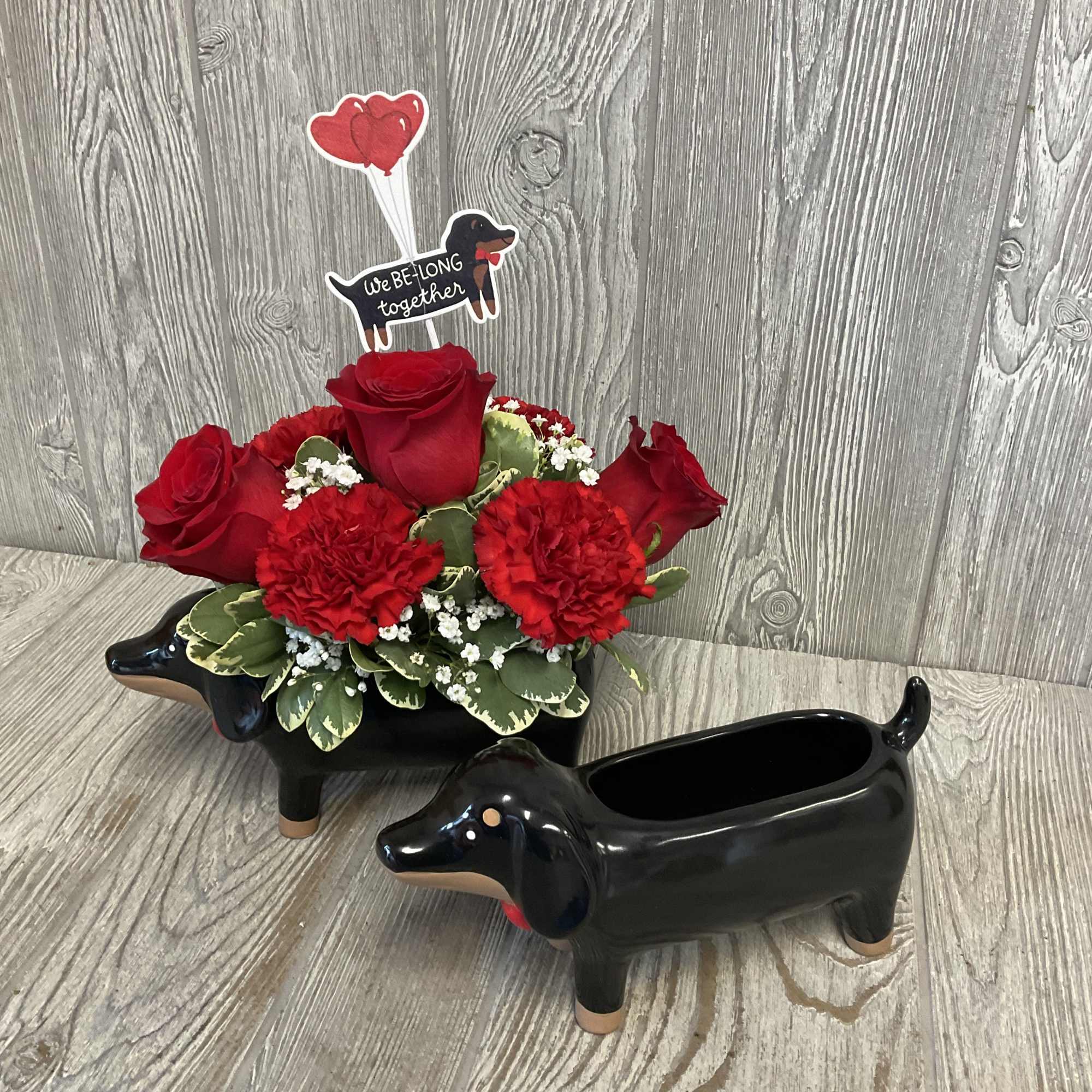 Red roses and carnations in a black dachshund planter with heart topper
