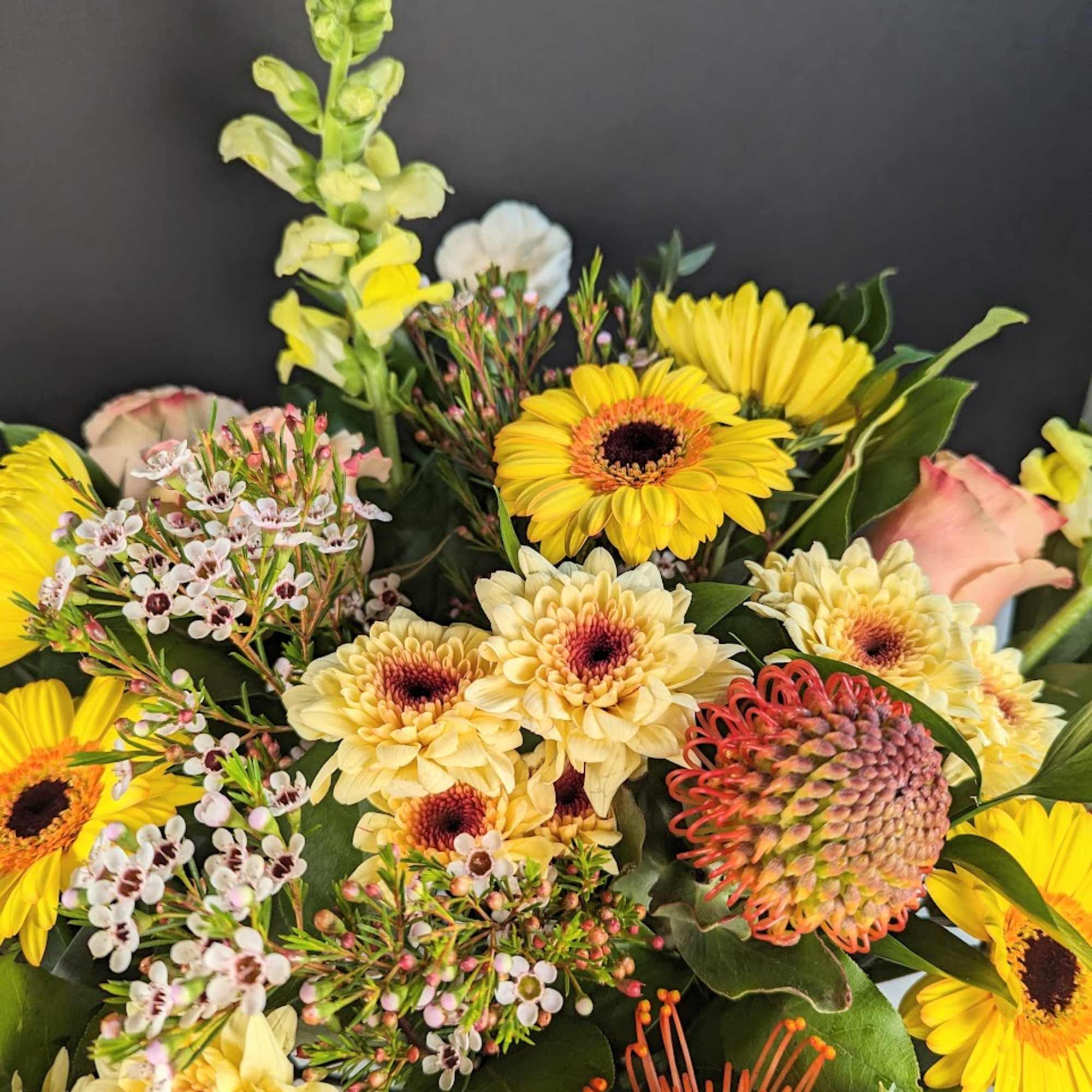 Mixed bouquet with yellow daisies, pale roses, and orange pincushion protea