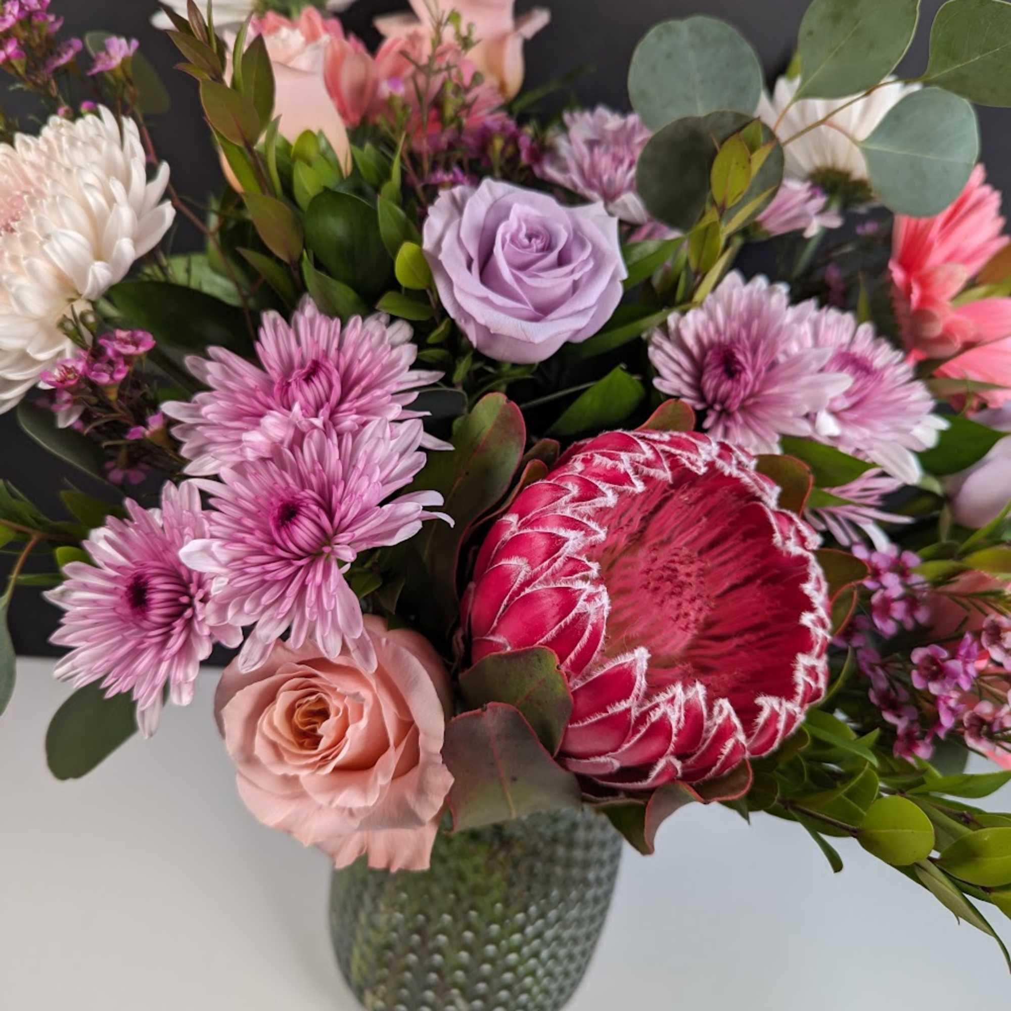 Mixed bouquet with pink and lavender flowers in a textured vase