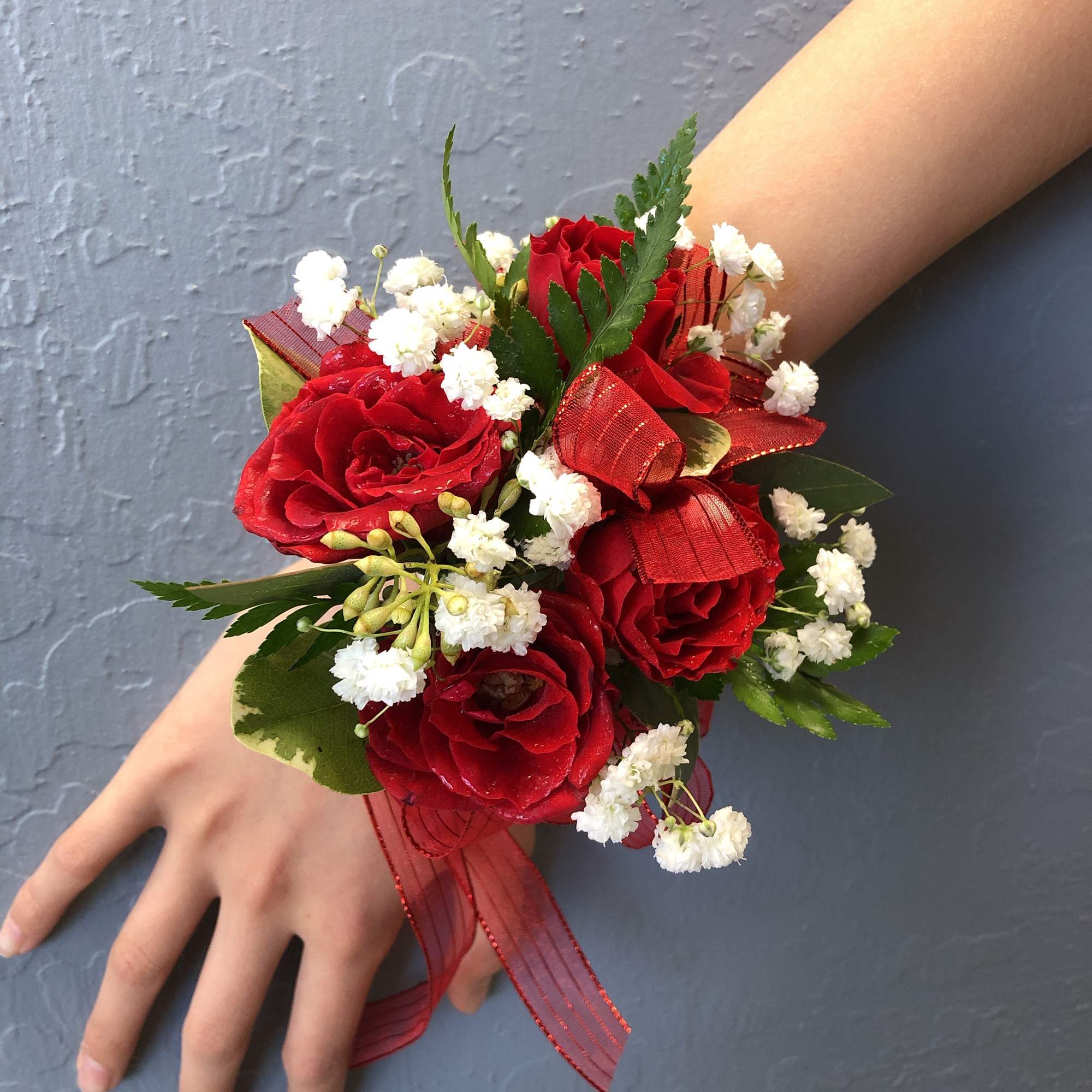 Red rose wrist corsage with white baby's breath and ribbon