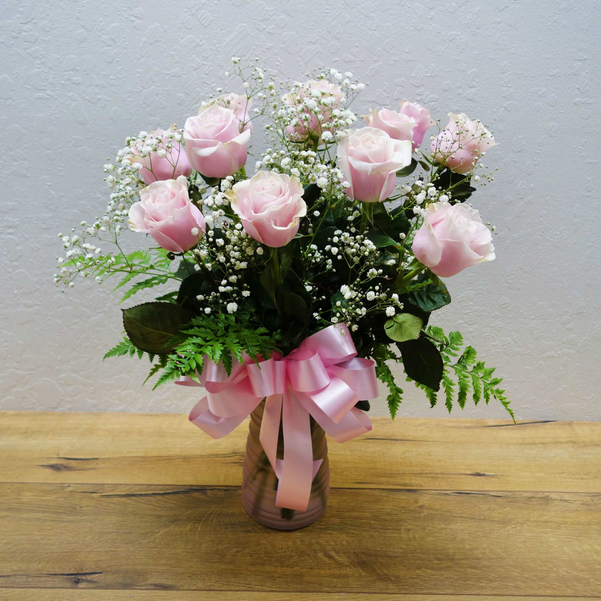 A dozen pink roses with variegated pittosporum and salal in a beautiful