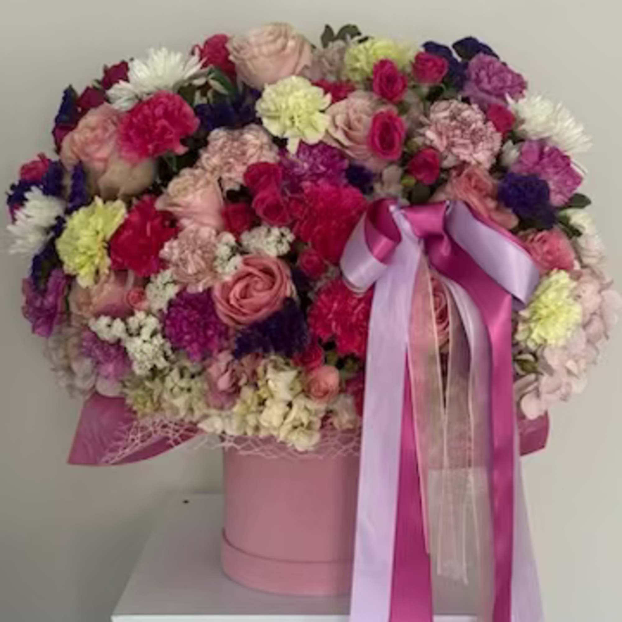 A lush, rounded bouquet arranged inside a round pink hat box-this gift-ready