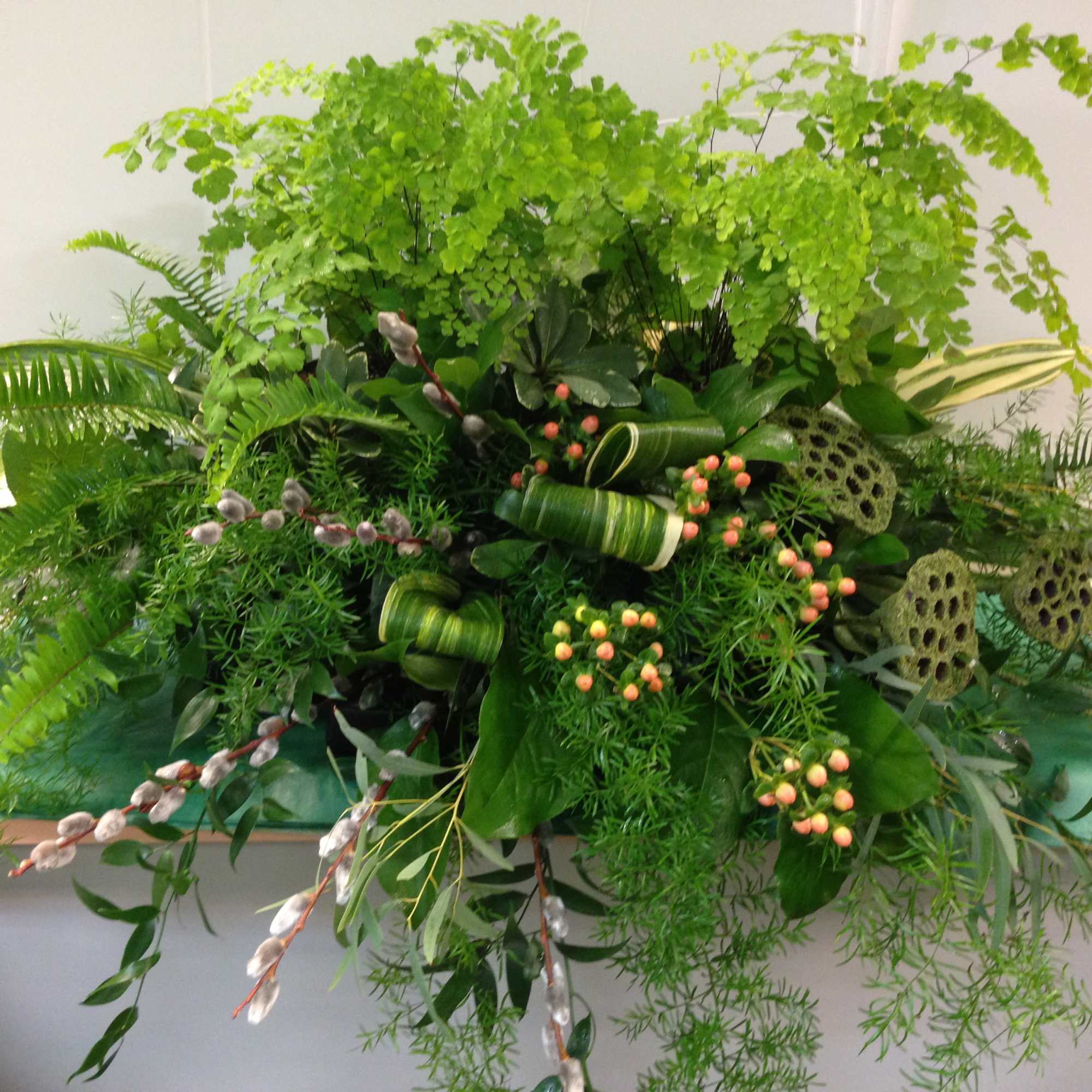 Large green floral arrangement with ferns and berry accents