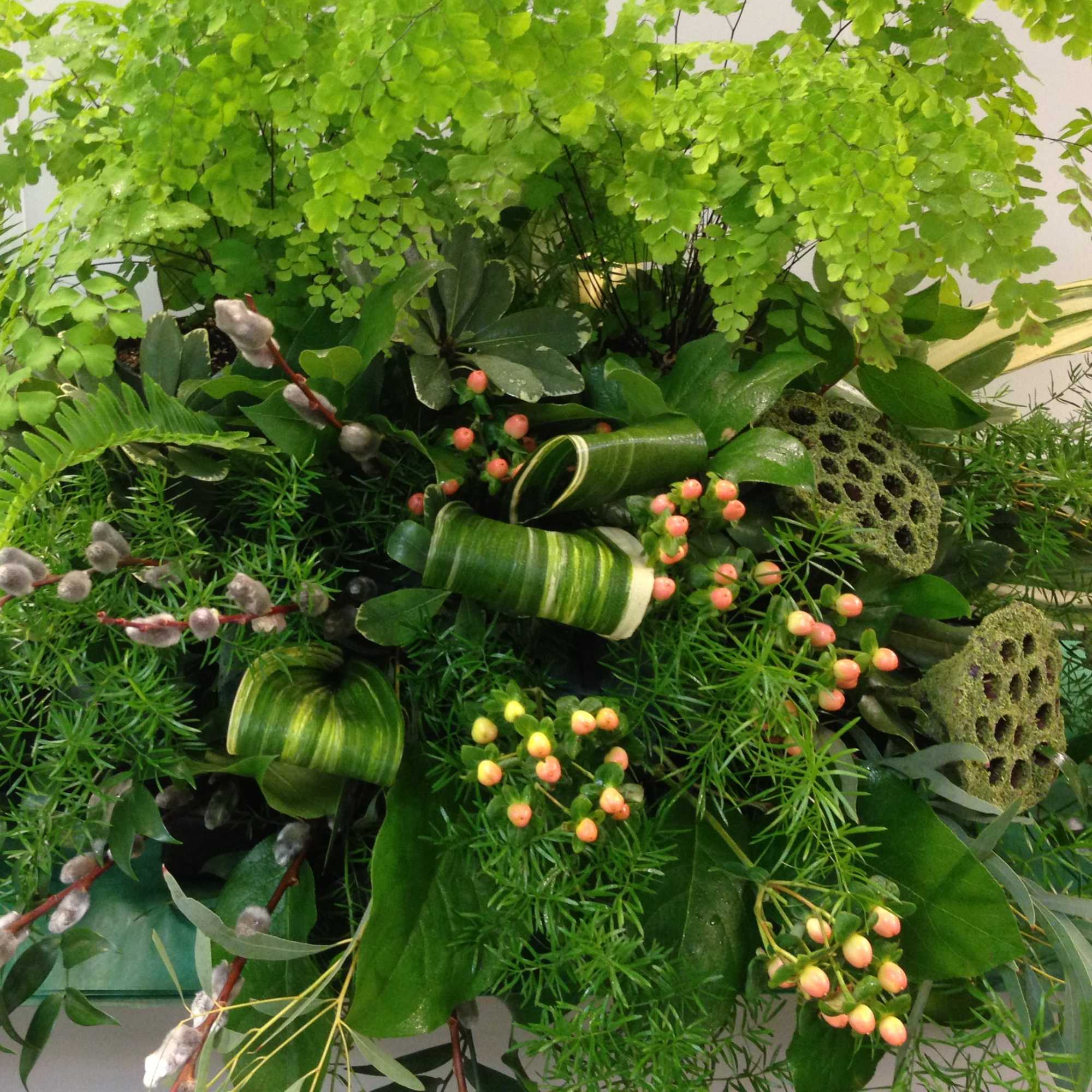 Lush green floral arrangement with fern-like foliage and berry accents