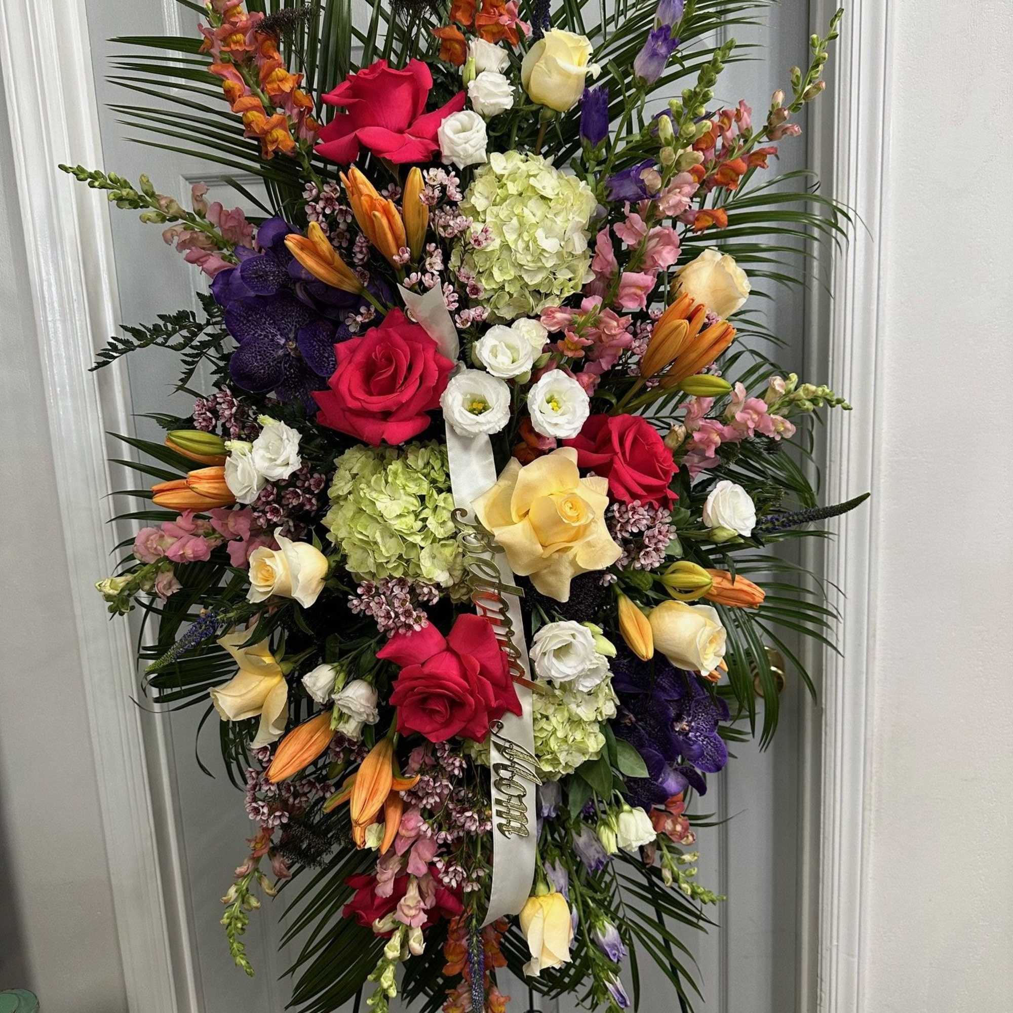 Tall standing floral spray with roses, lilies, hydrangeas, and orchids