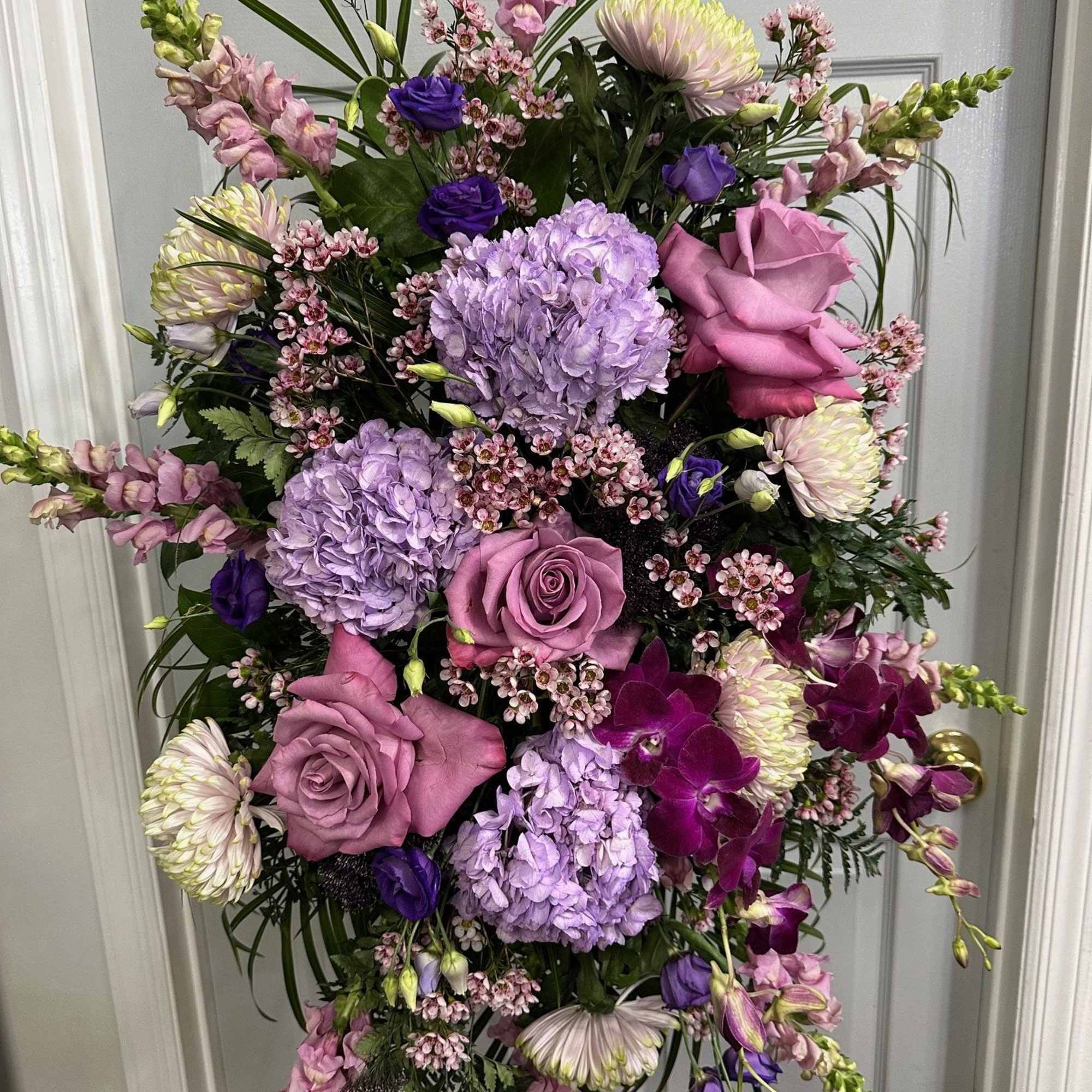 Lavender and pink floral standing spray with roses, hydrangeas, orchids, and snapdragons