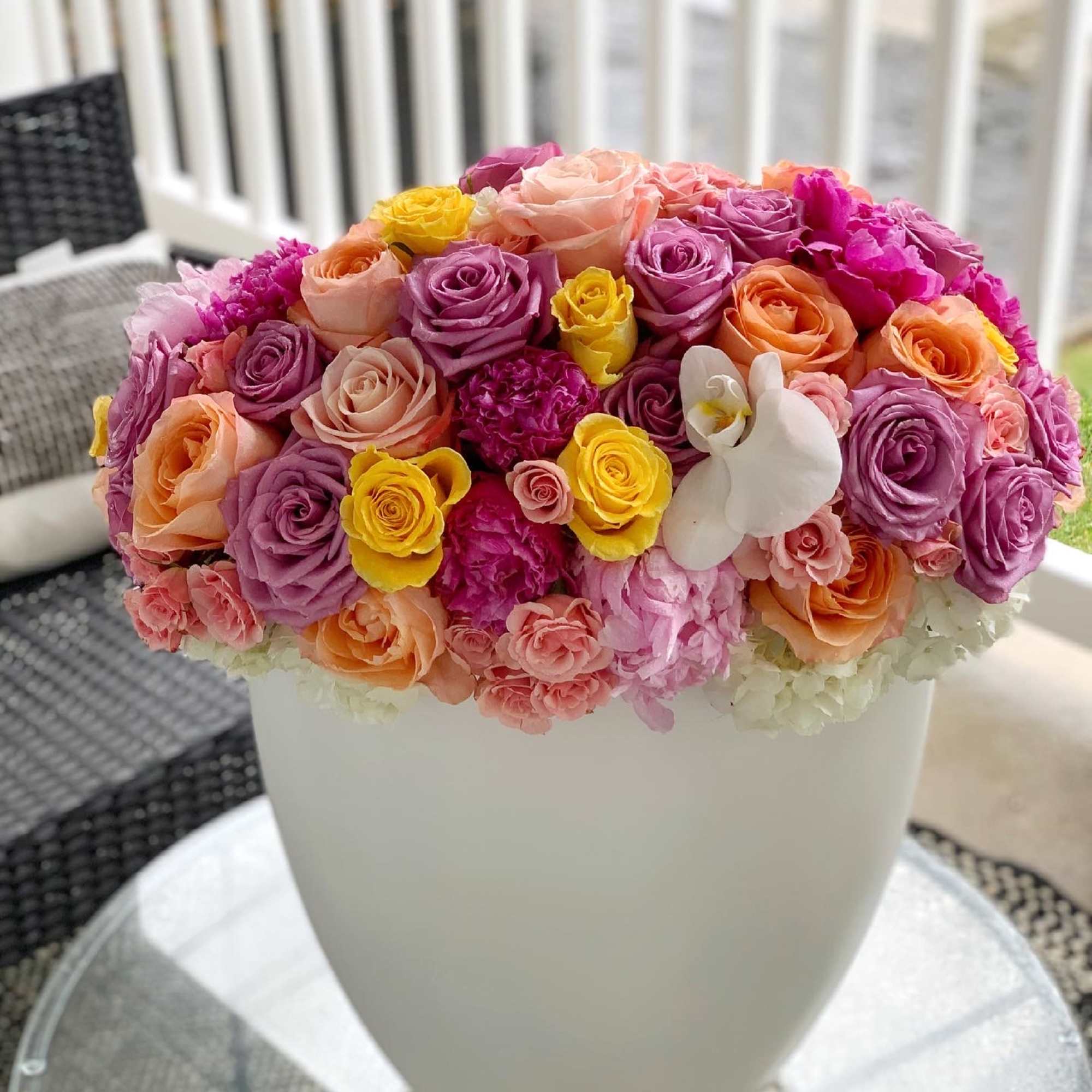 Colorful bouquet of roses and orchids in a white vase