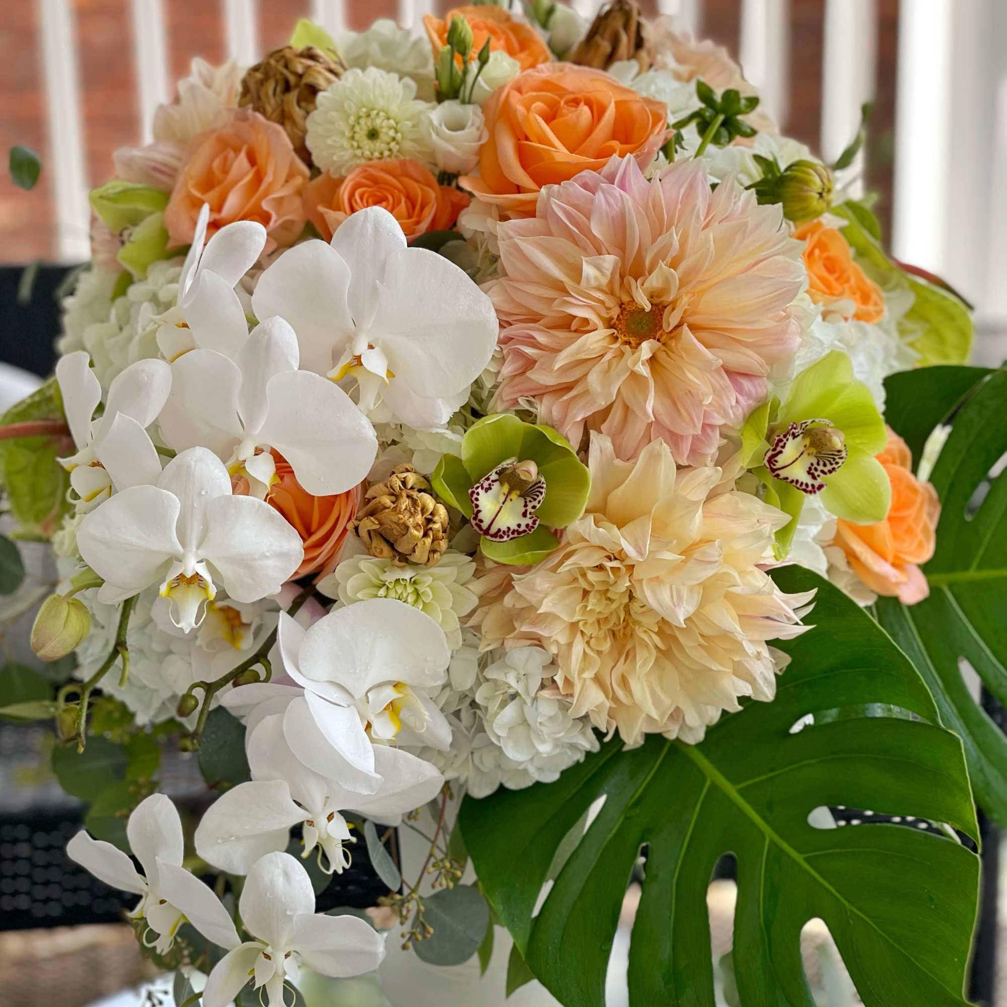 Bouquet of white orchids, peach roses, and cream dahlias in a white vase