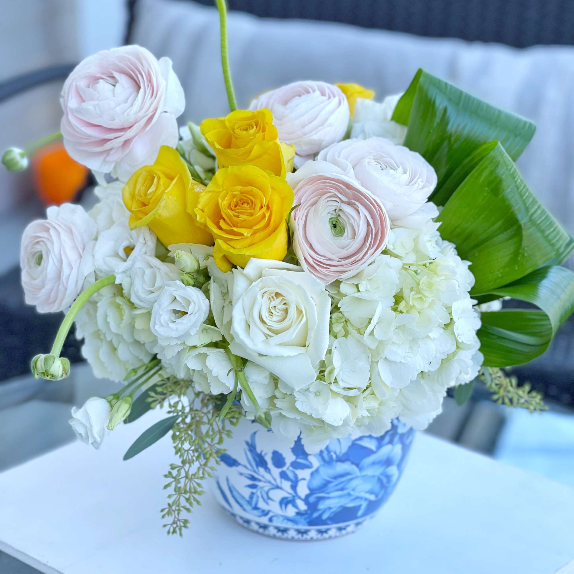Bouquet of yellow, white, and pale pink roses in a blue-and-white vase