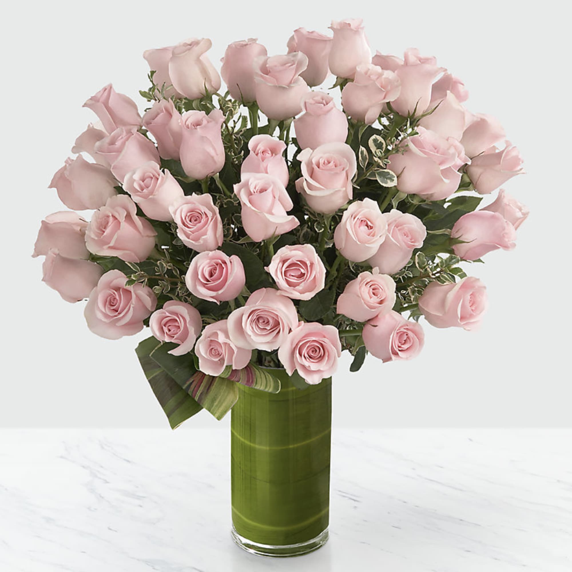 Bouquet of pale pink roses in a tall green glass vase