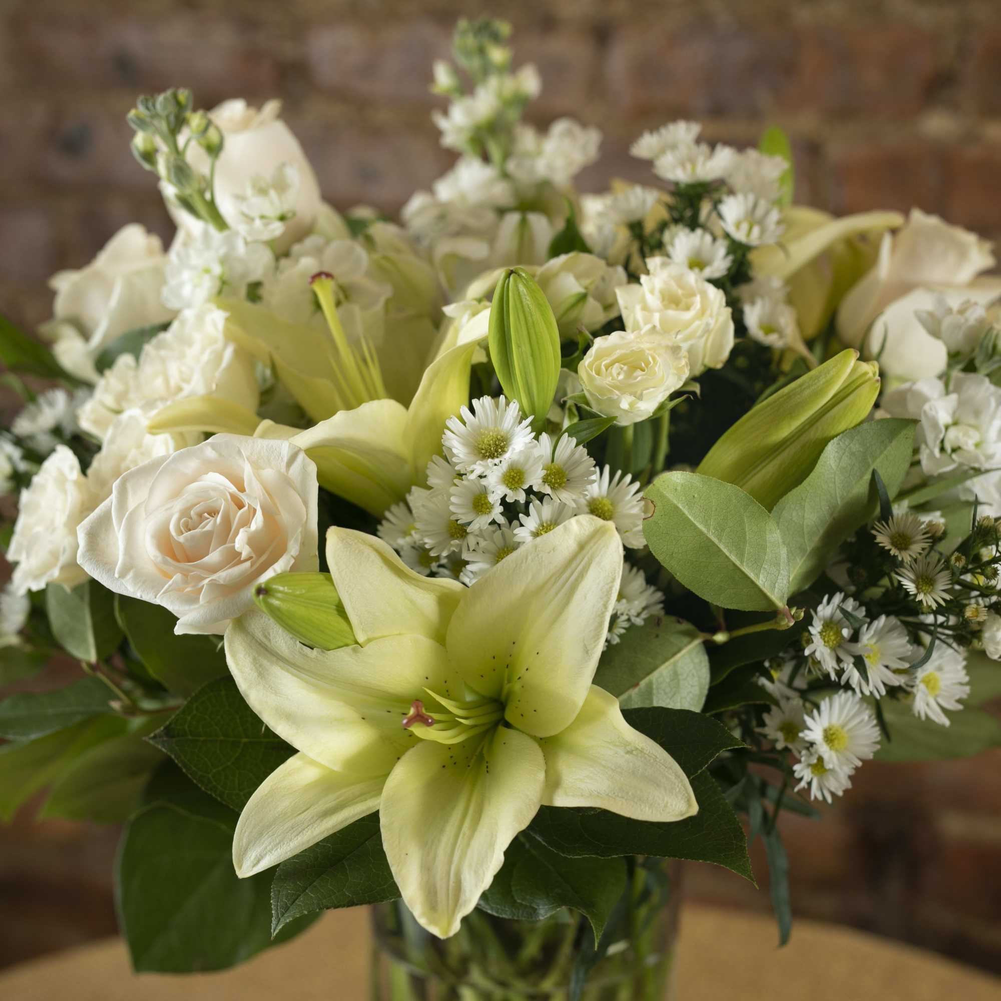 White lilies and roses arranged in a glass vase