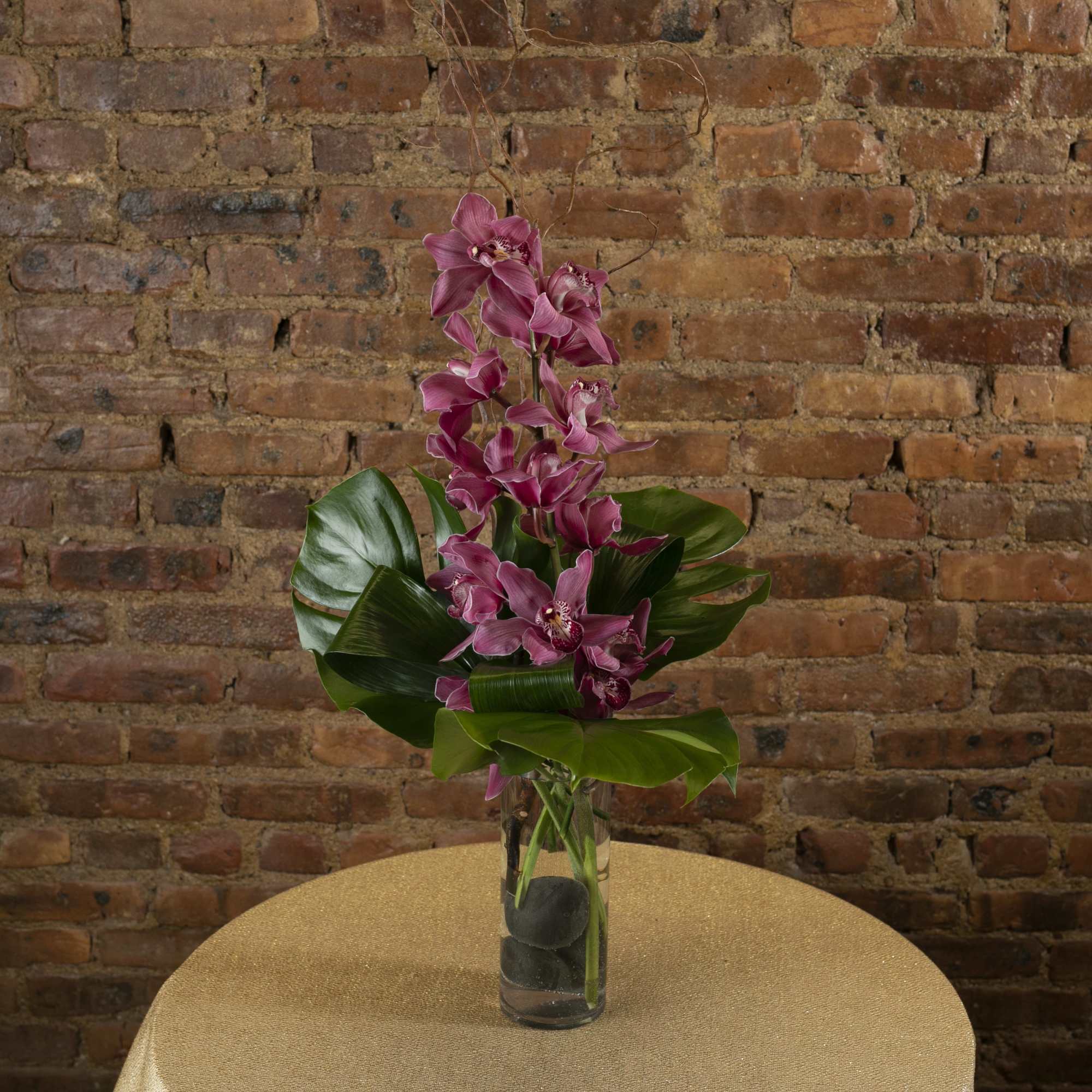 Tall purple orchid arrangement in a clear glass vase