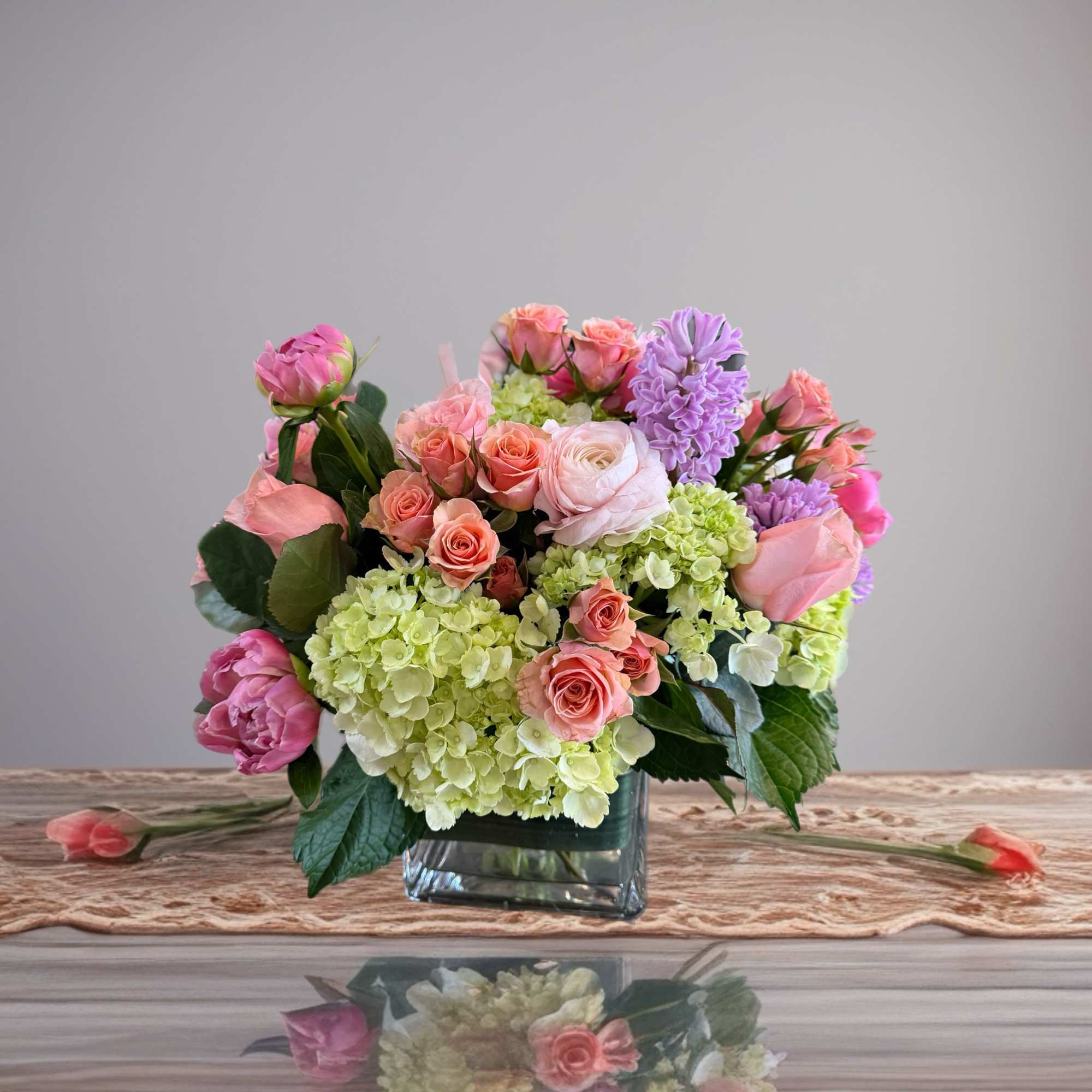 Pink and lavender flowers arranged in a square glass vase