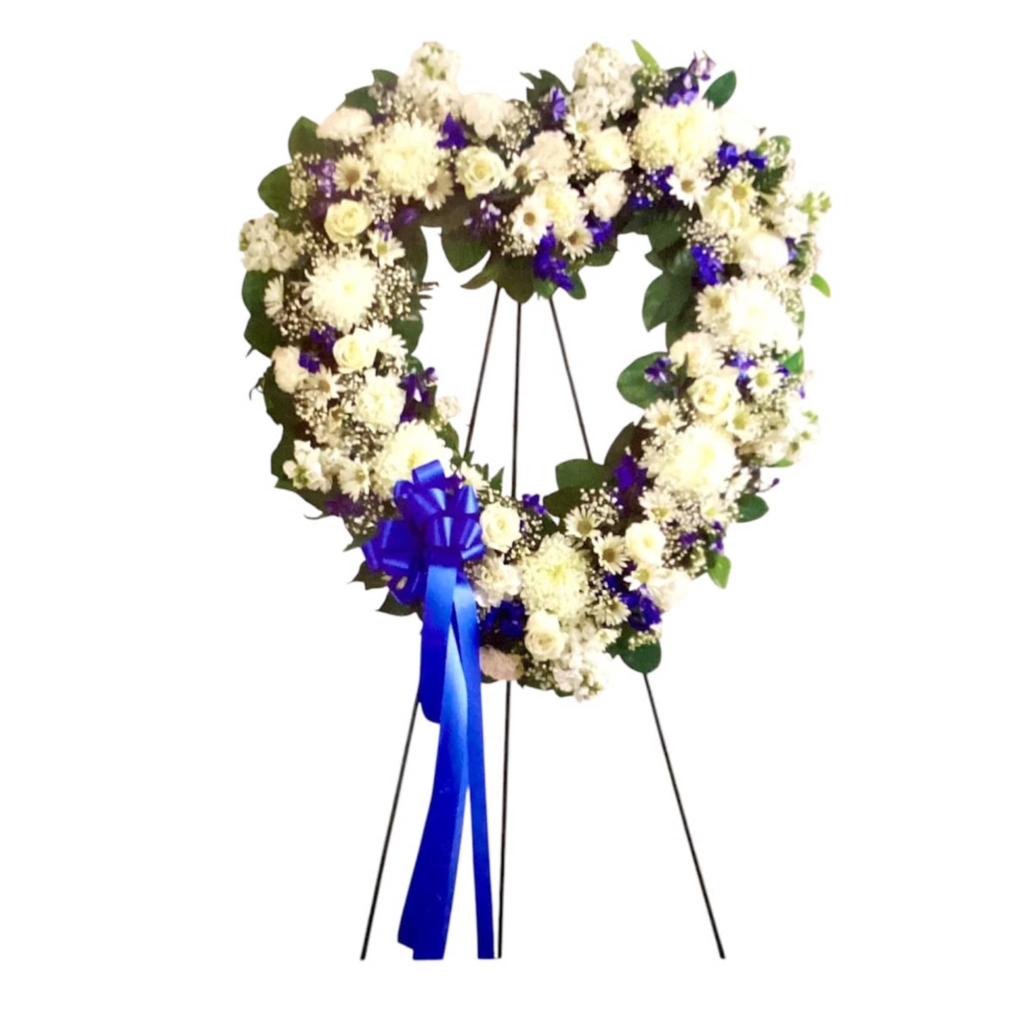 Heart-shaped white floral wreath on a stand with a blue ribbon