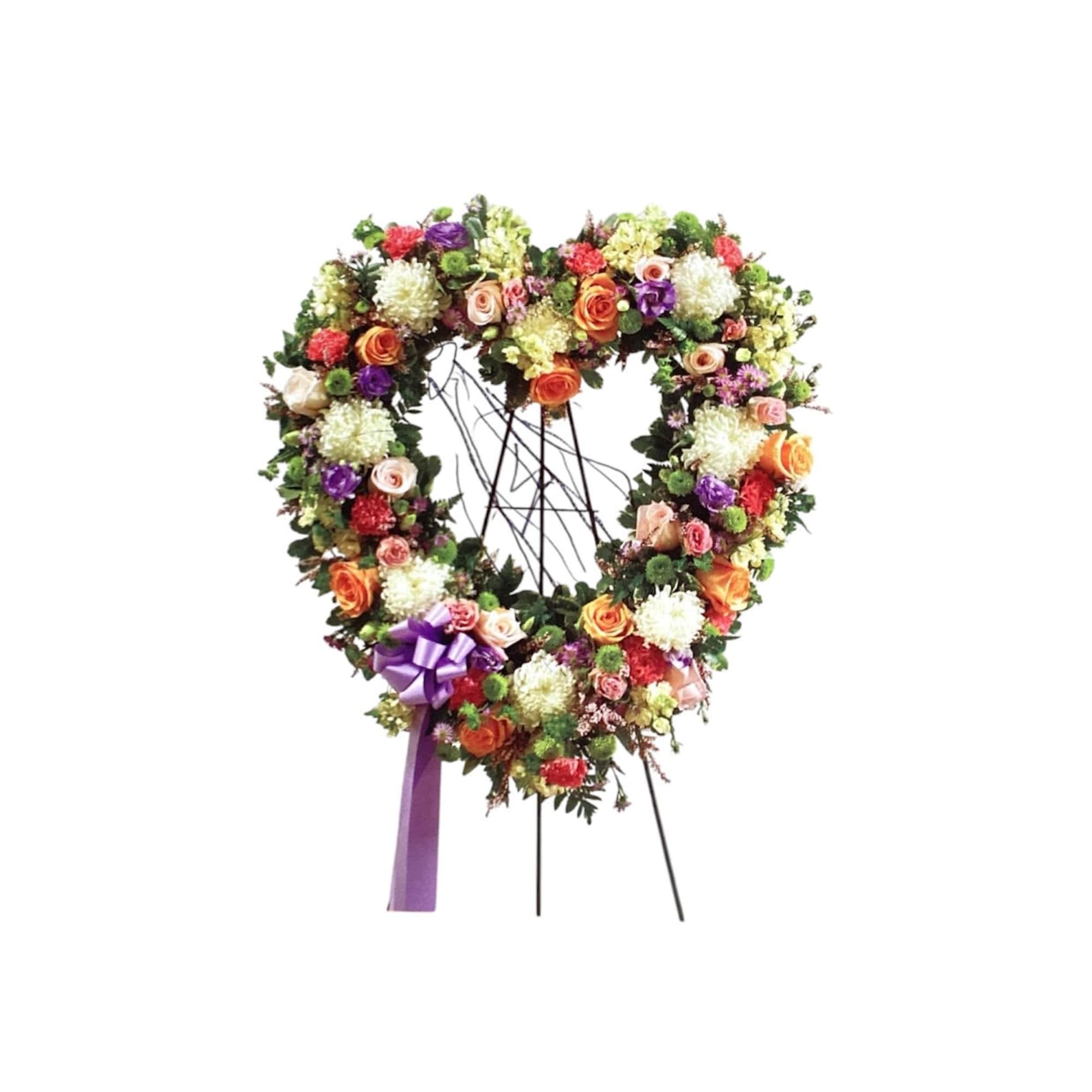 Heart-shaped floral wreath on a stand with a purple ribbon