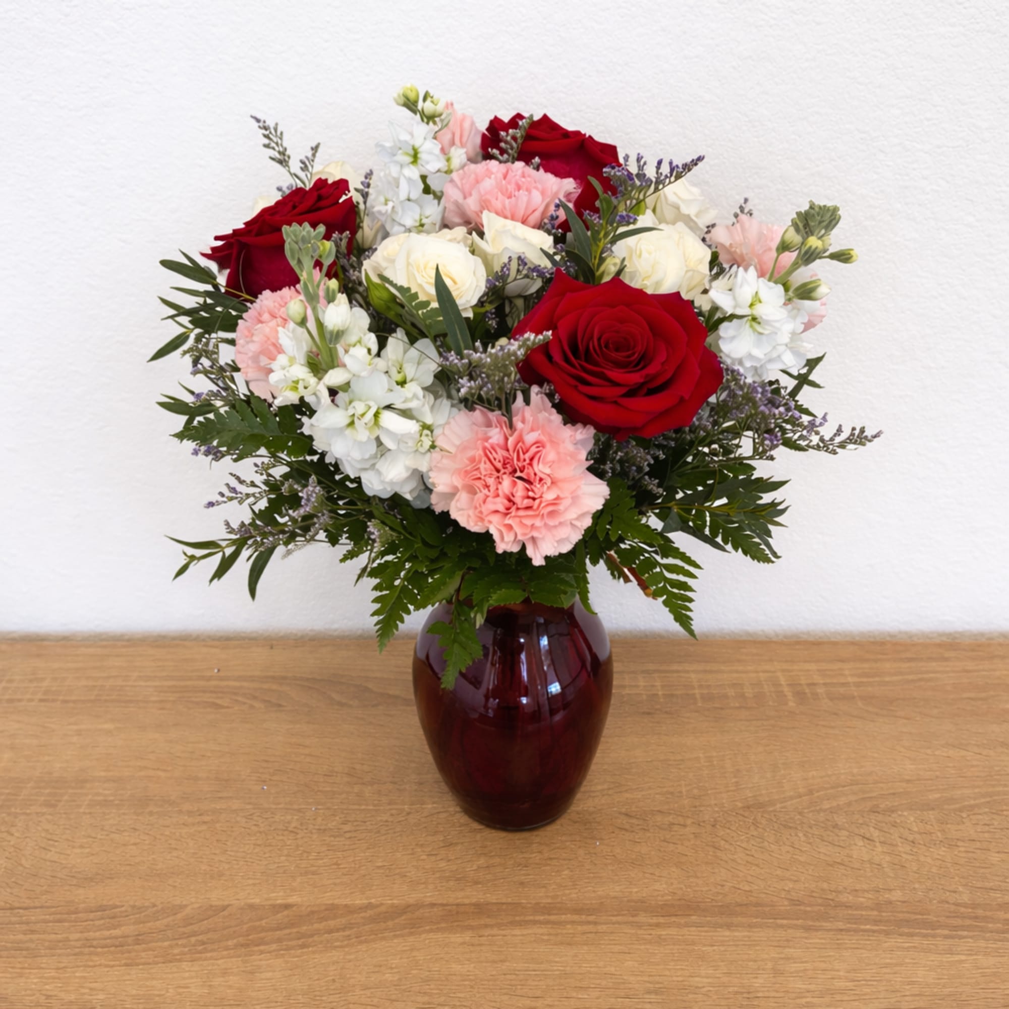 Bouquet of red and white roses with pink carnations in a burgundy vase