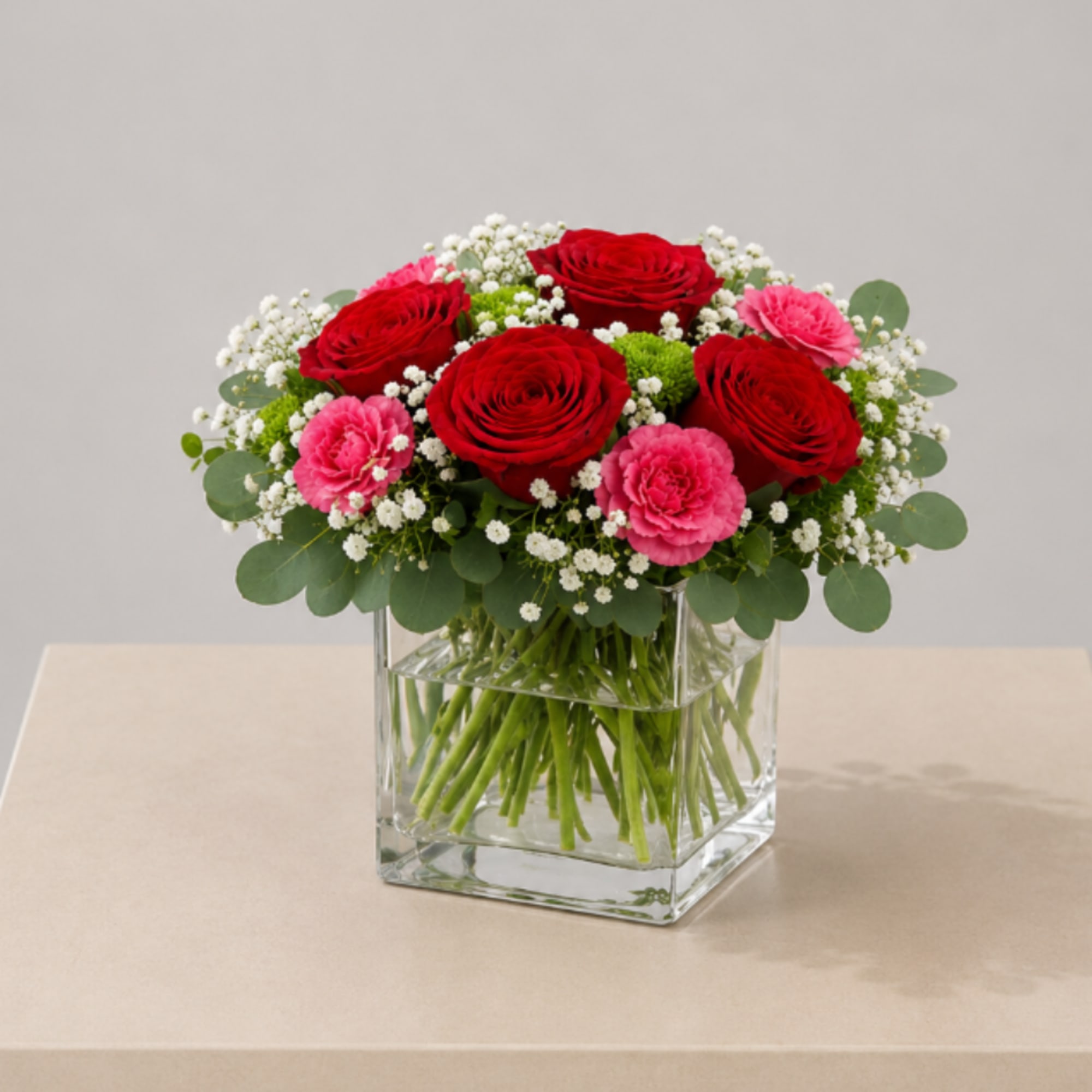 A romantic flower arrangement designed in a modern glass cube, featuring rich
