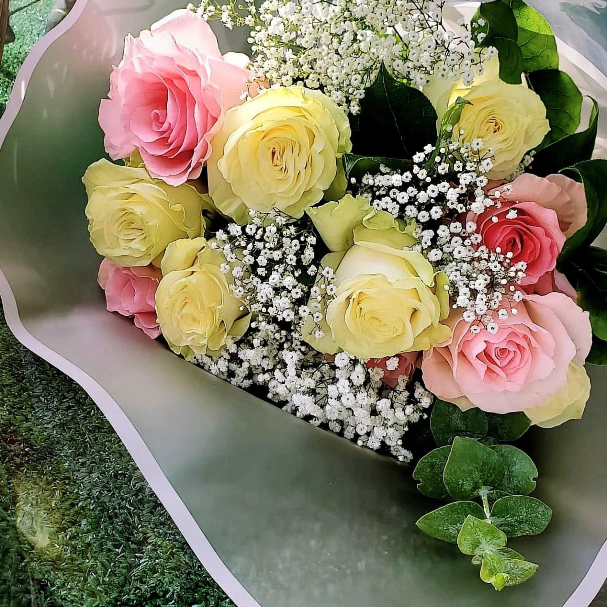 Bouquet of pink and yellow roses with baby's breath in pink wrap