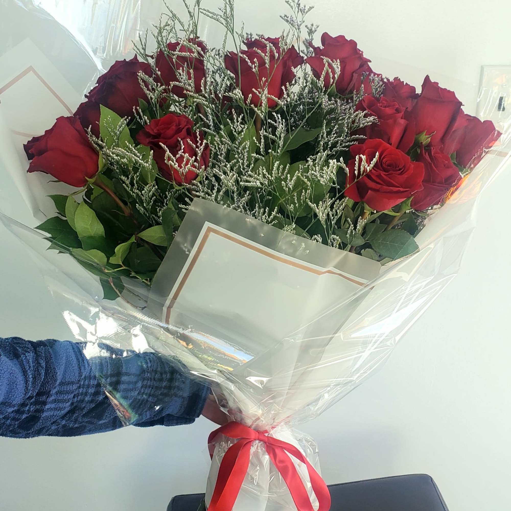 Bouquet of red roses wrapped in clear plastic with a red ribbon