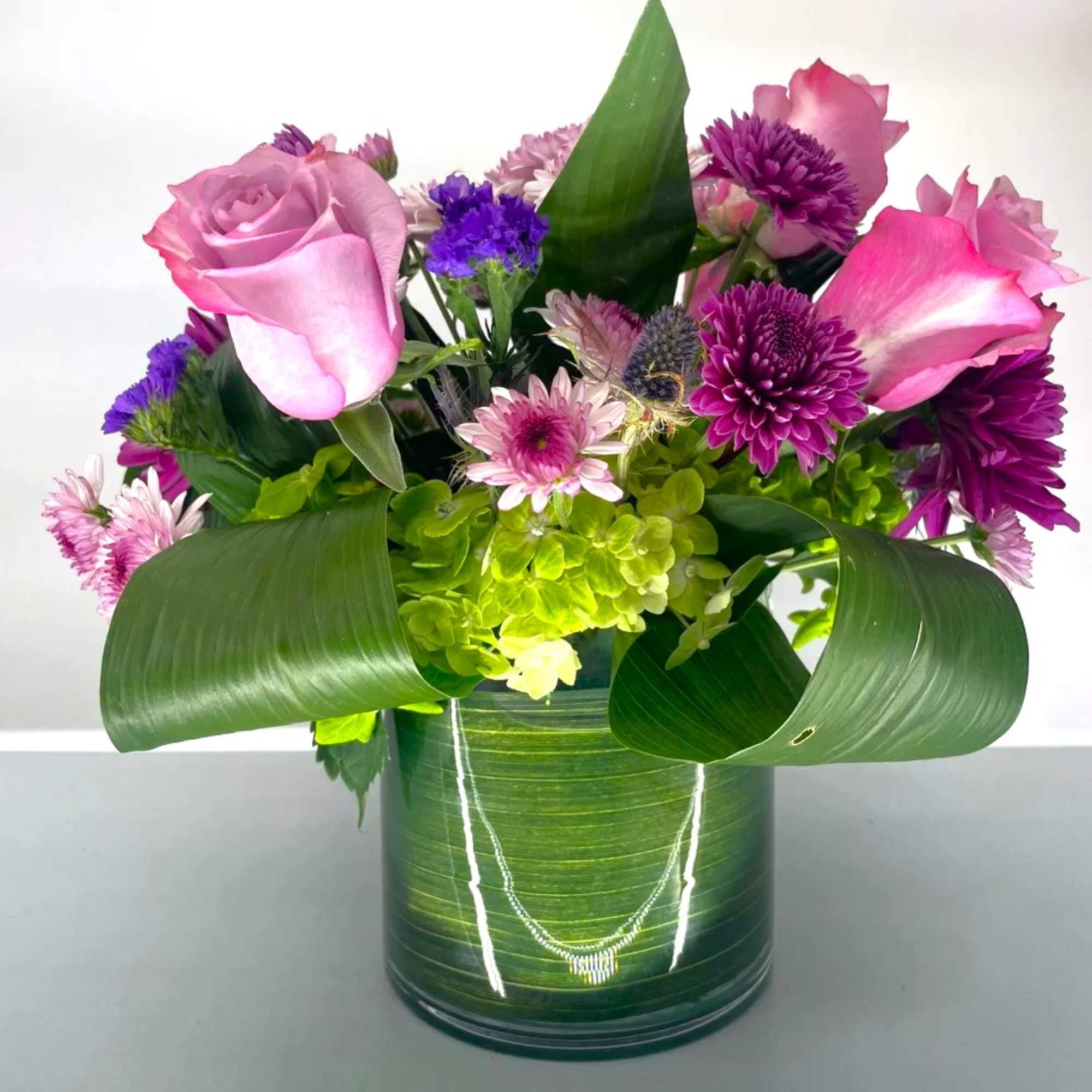 Pink roses and purple flowers in a green vase