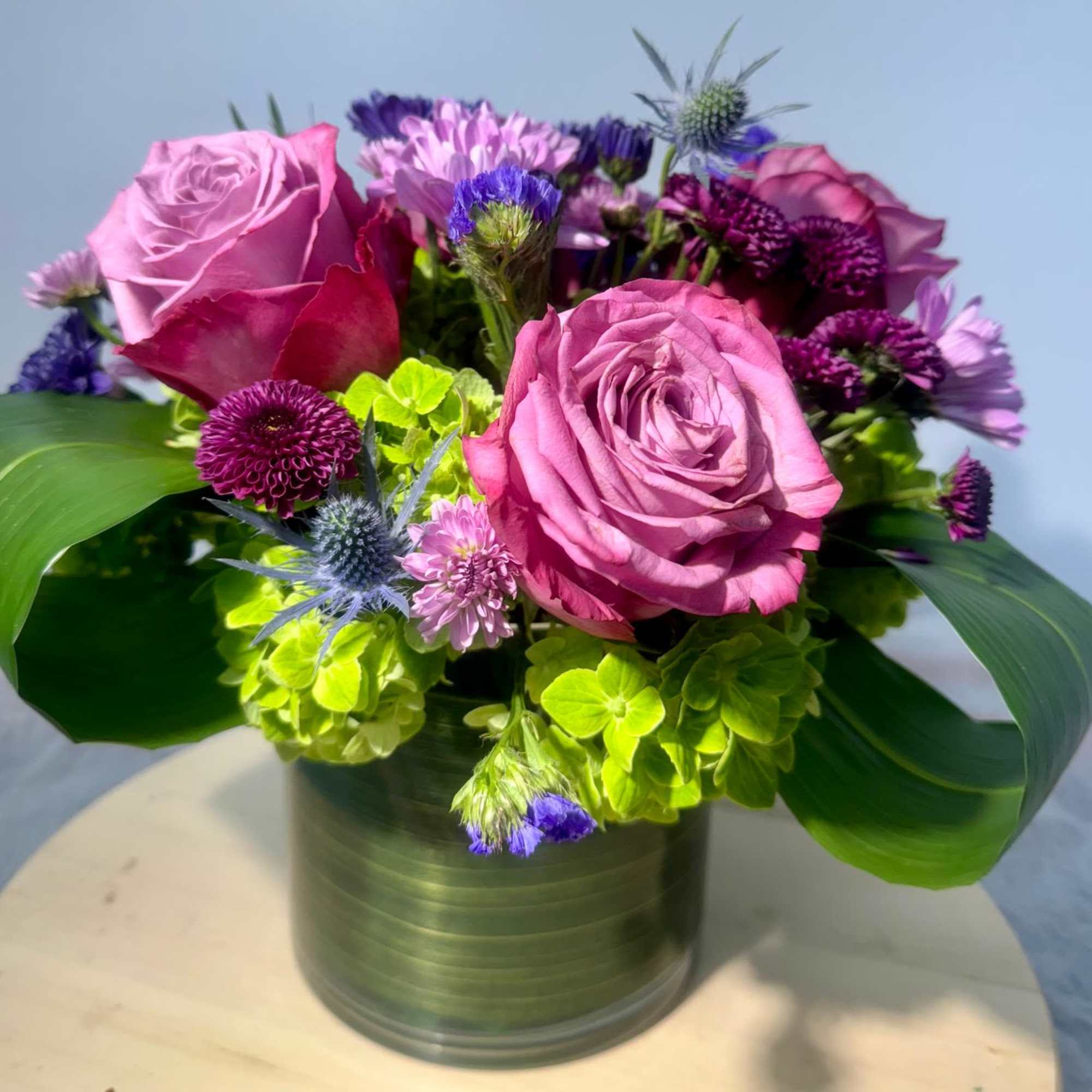 Pink roses and purple flowers arranged in a metal vase