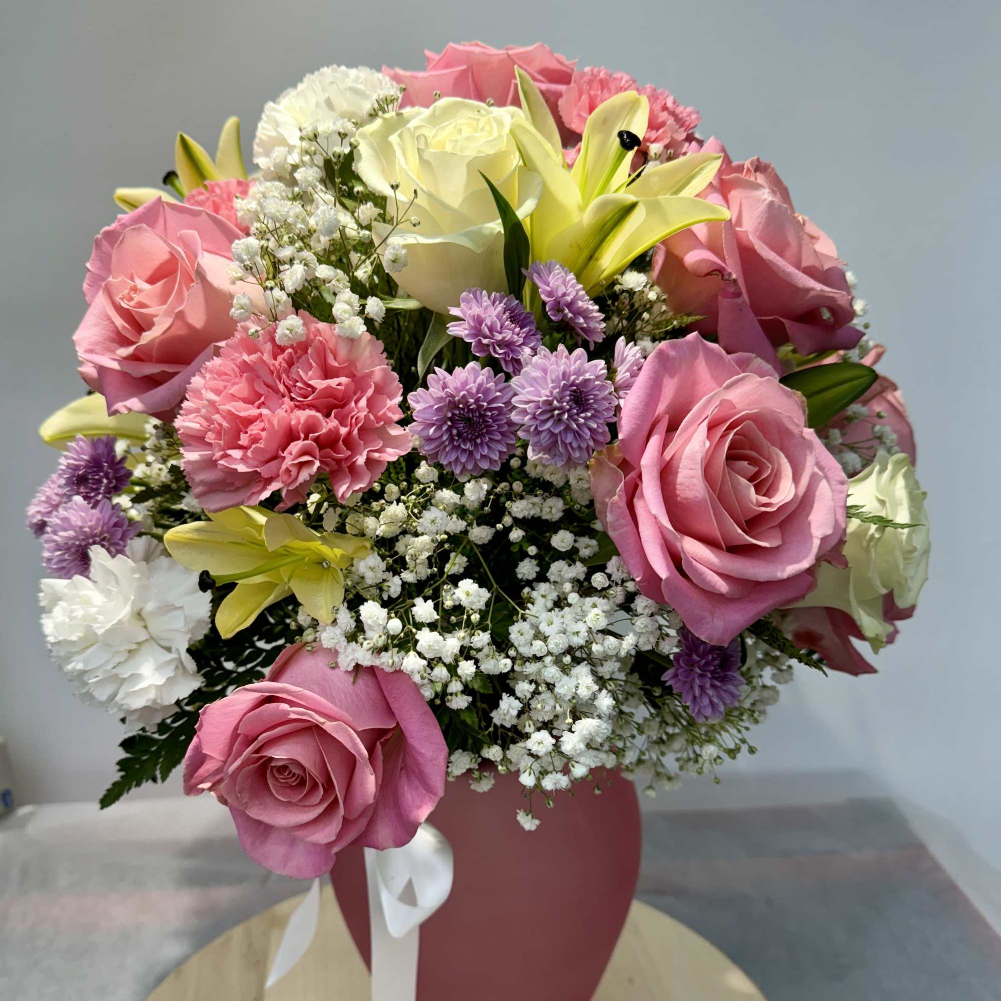 Pink and white rose bouquet with lilies and purple flowers in a pink vase