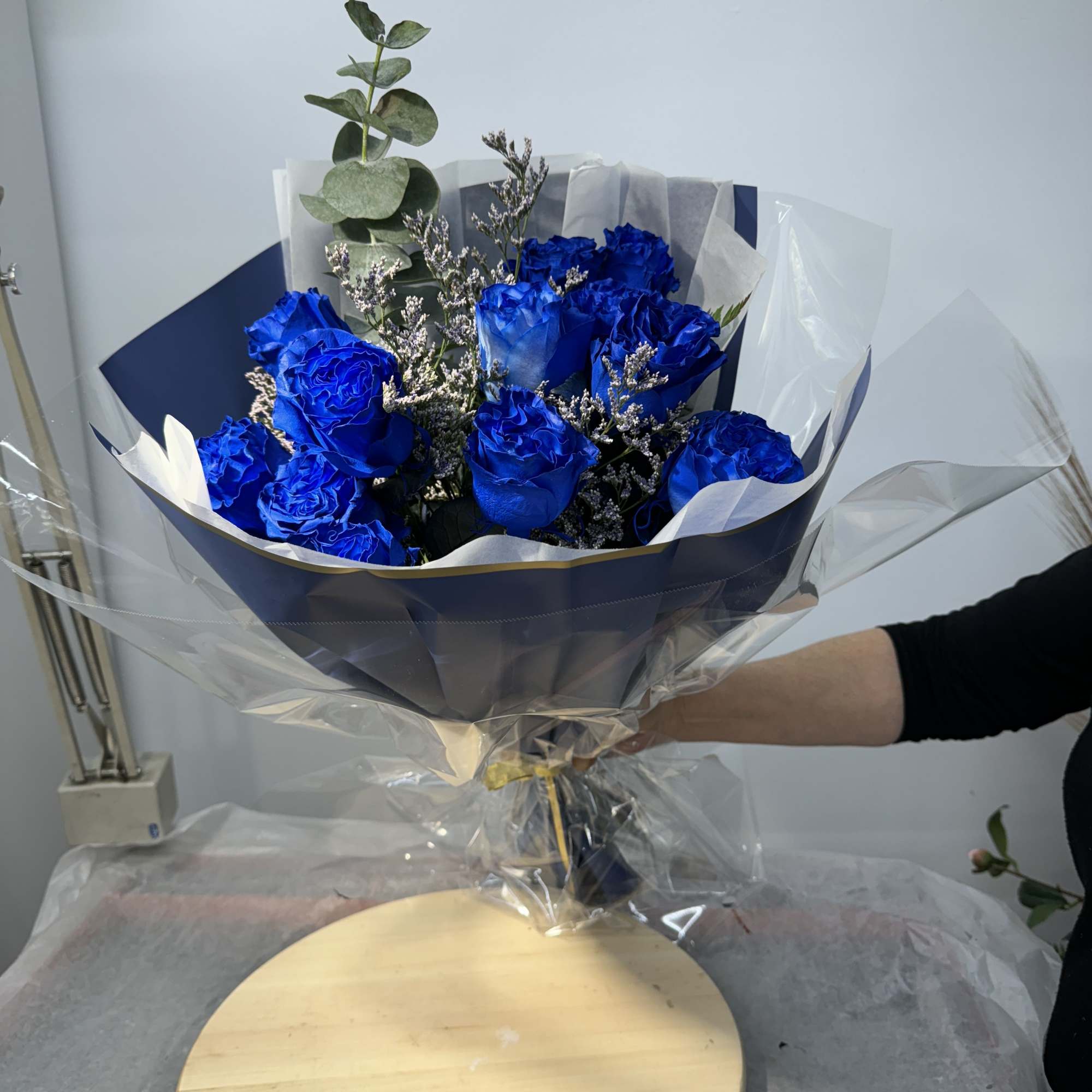 Bouquet of vivid blue roses wrapped in navy and clear paper