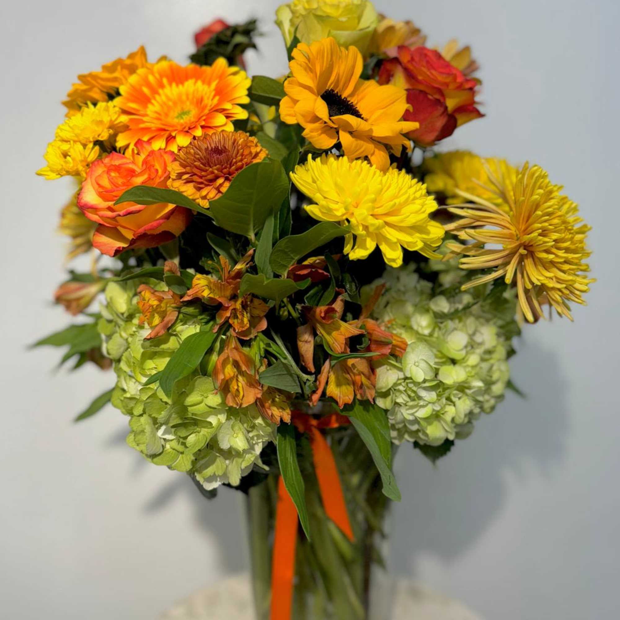 Mixed bouquet of yellow, orange, and red flowers in a glass vase