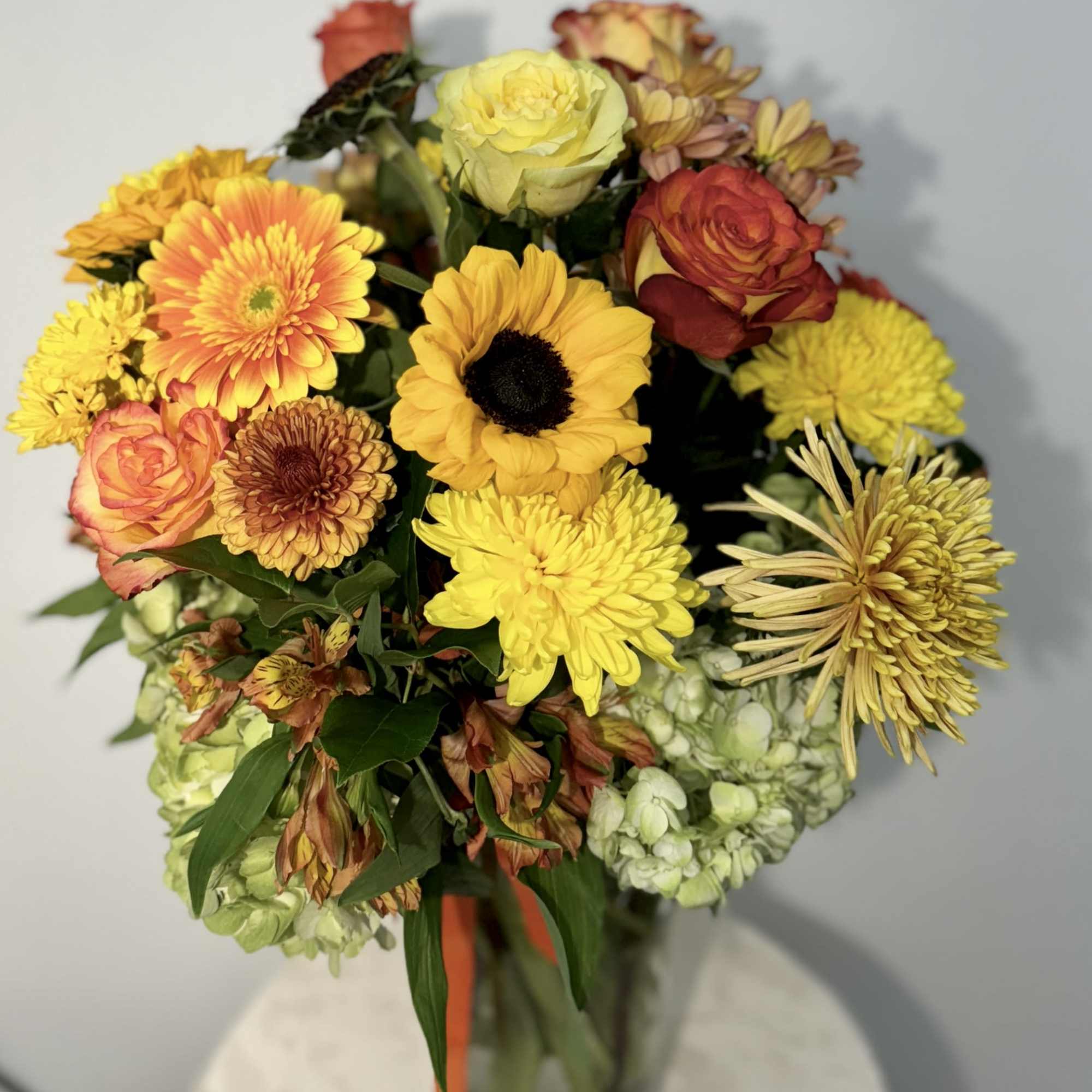 Mixed bouquet of yellow and orange flowers in a glass vase, photo 2 of 3