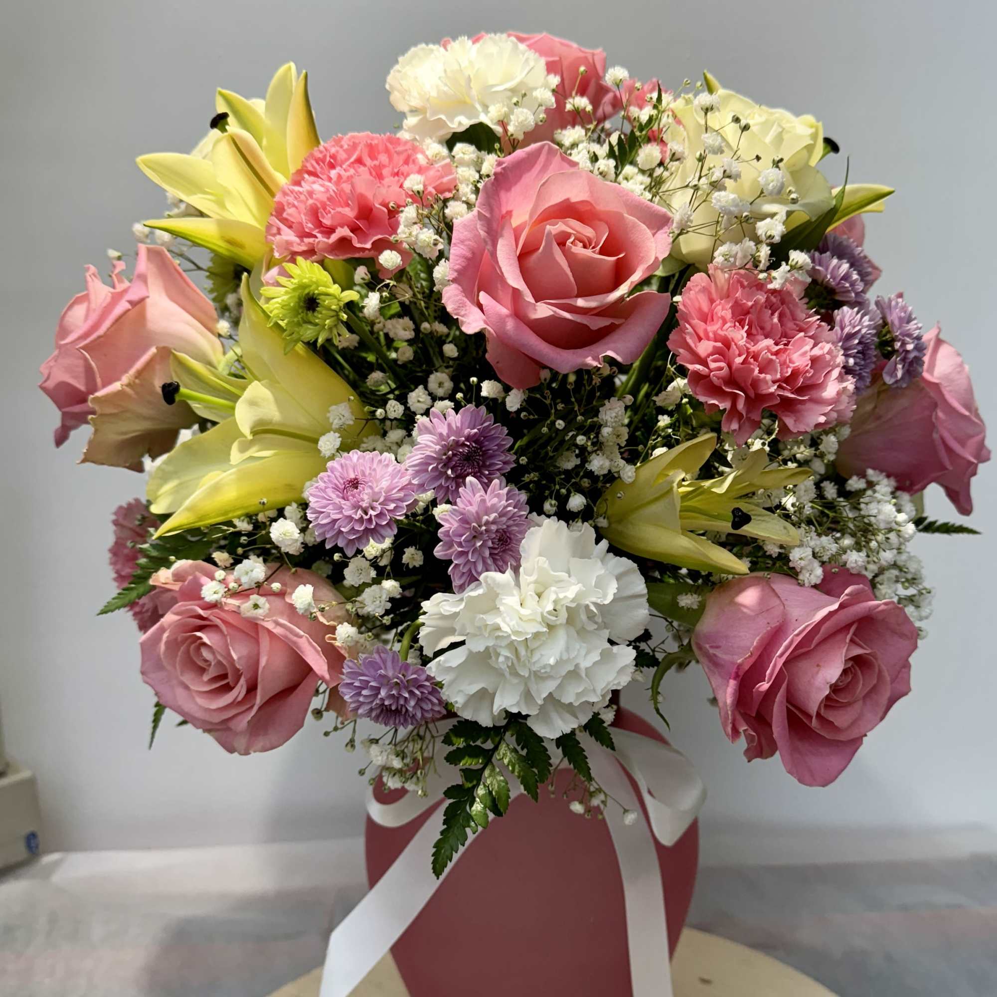 Pink and white mixed bouquet in a pink vase with ribbon