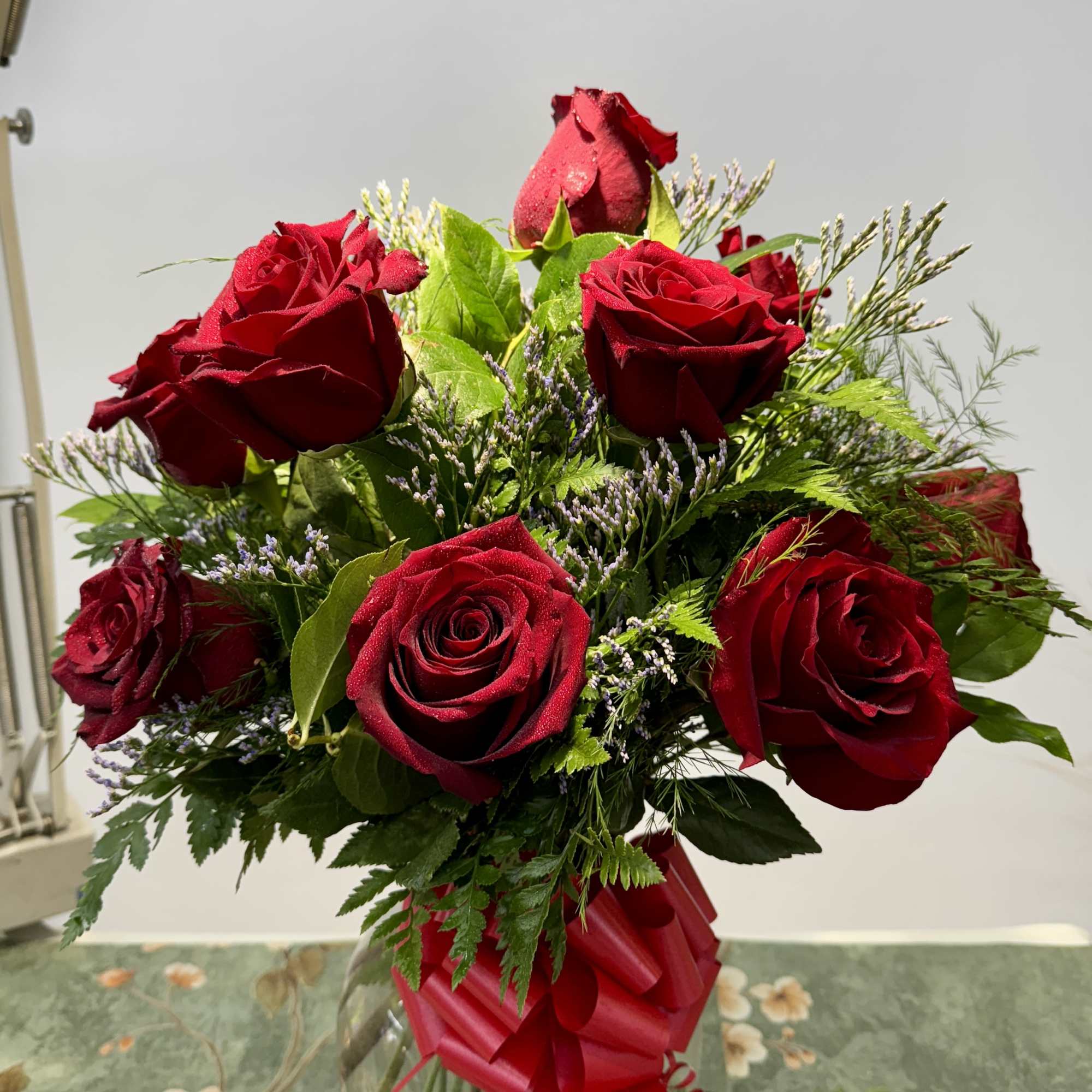Red roses arranged in a clear glass vase with a red ribbon