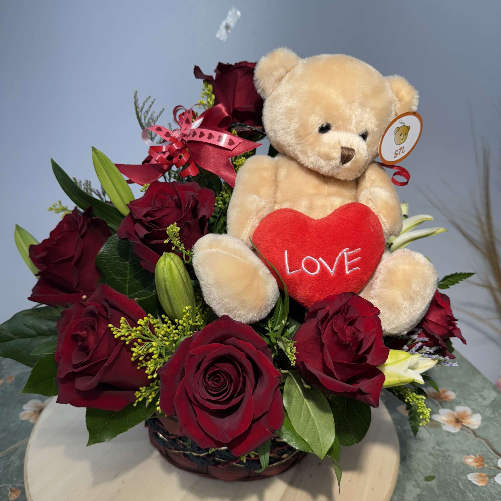 Red rose arrangement with a teddy bear holding a heart