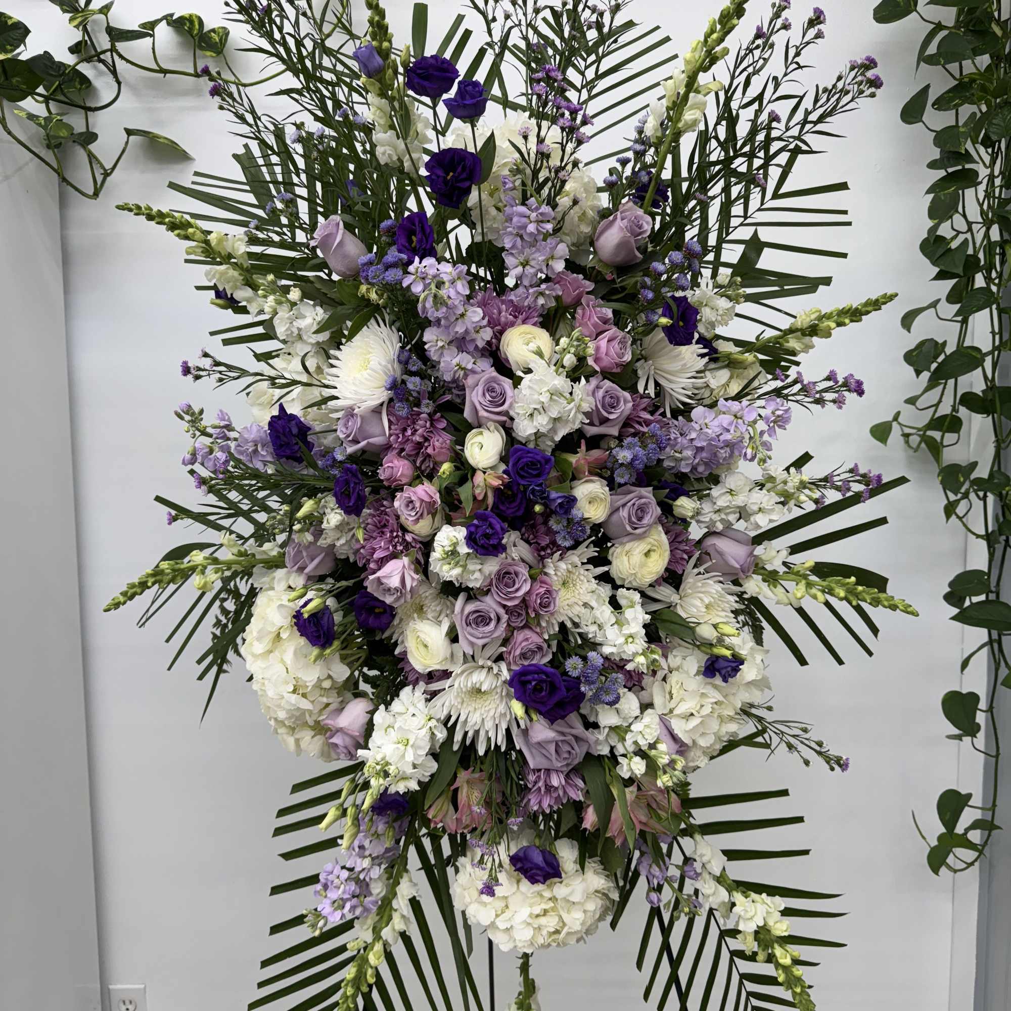 Large standing floral spray with purple, lavender, and white blooms