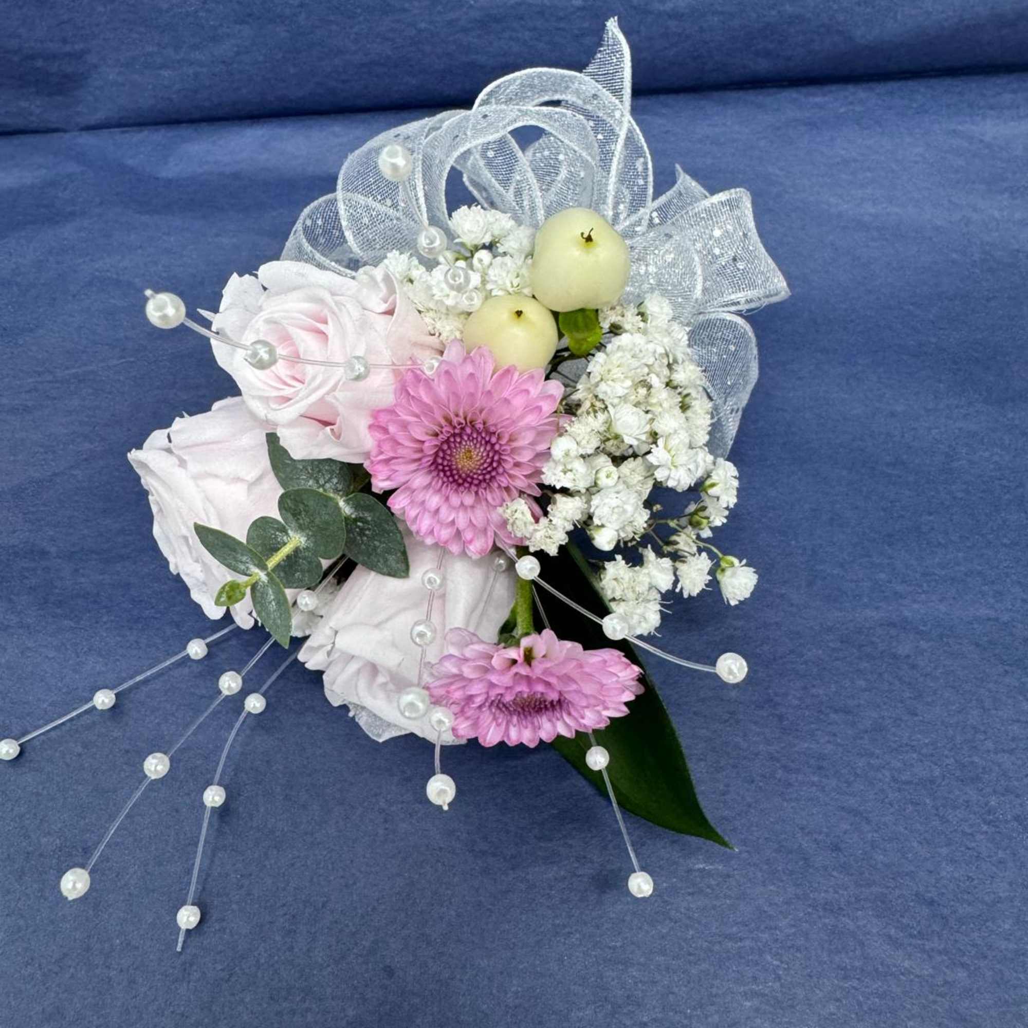 Pink and white floral corsage with pearl accents and silver ribbon