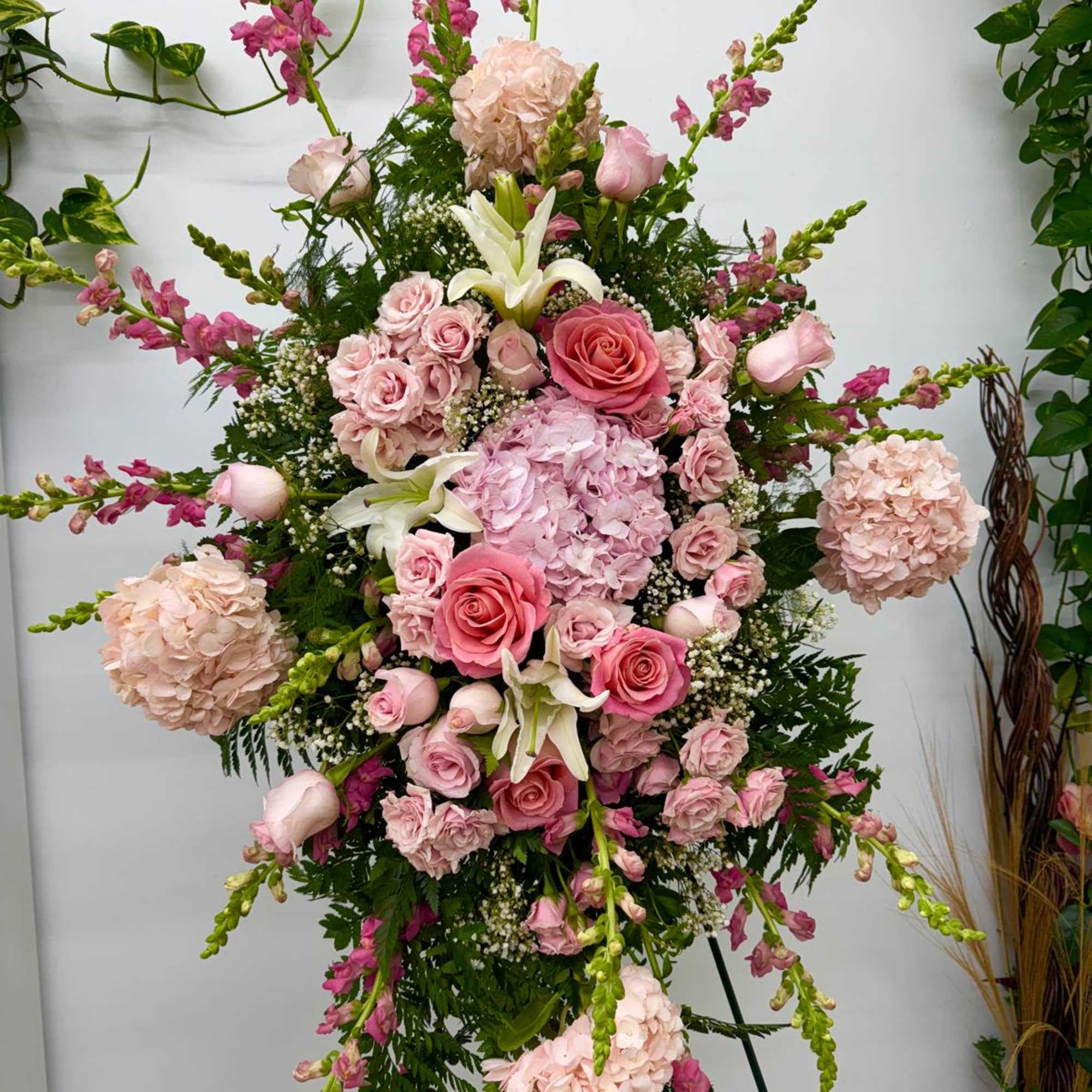 Tall pink floral standing arrangement with roses, hydrangeas, lilies, and snapdragons