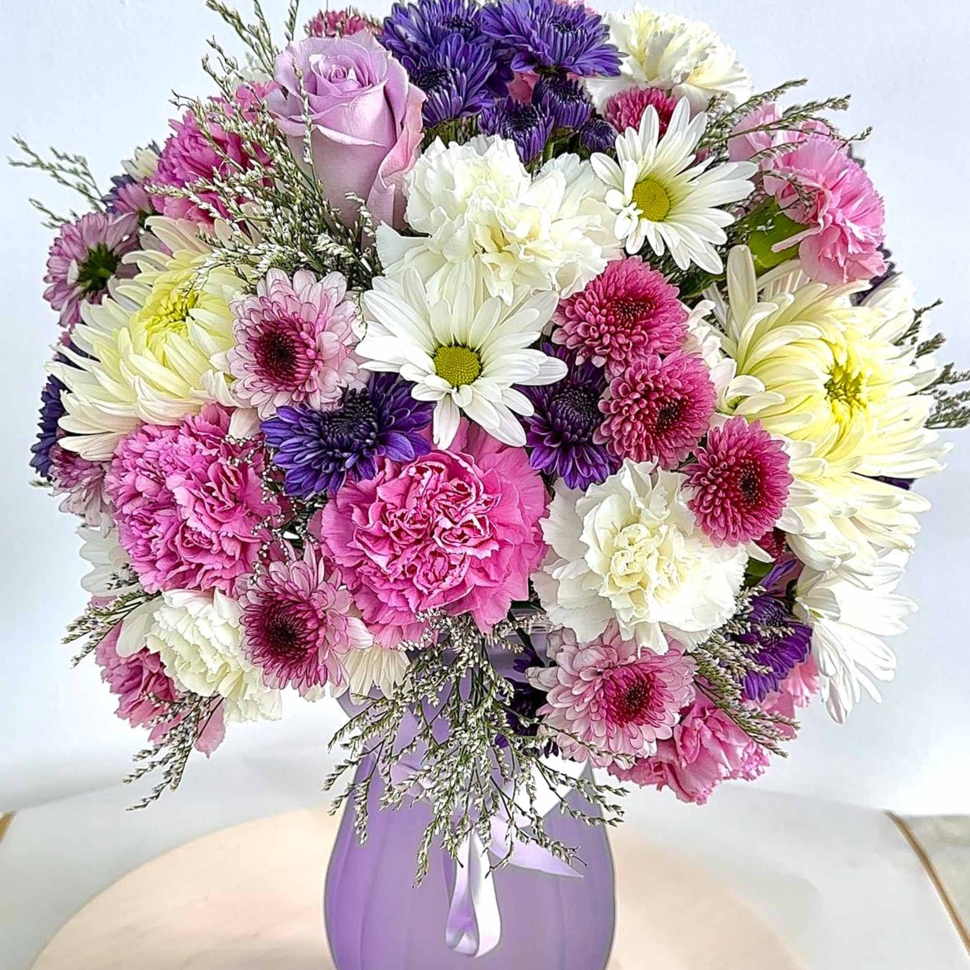 Mixed pink, white, and purple bouquet in a lavender vase