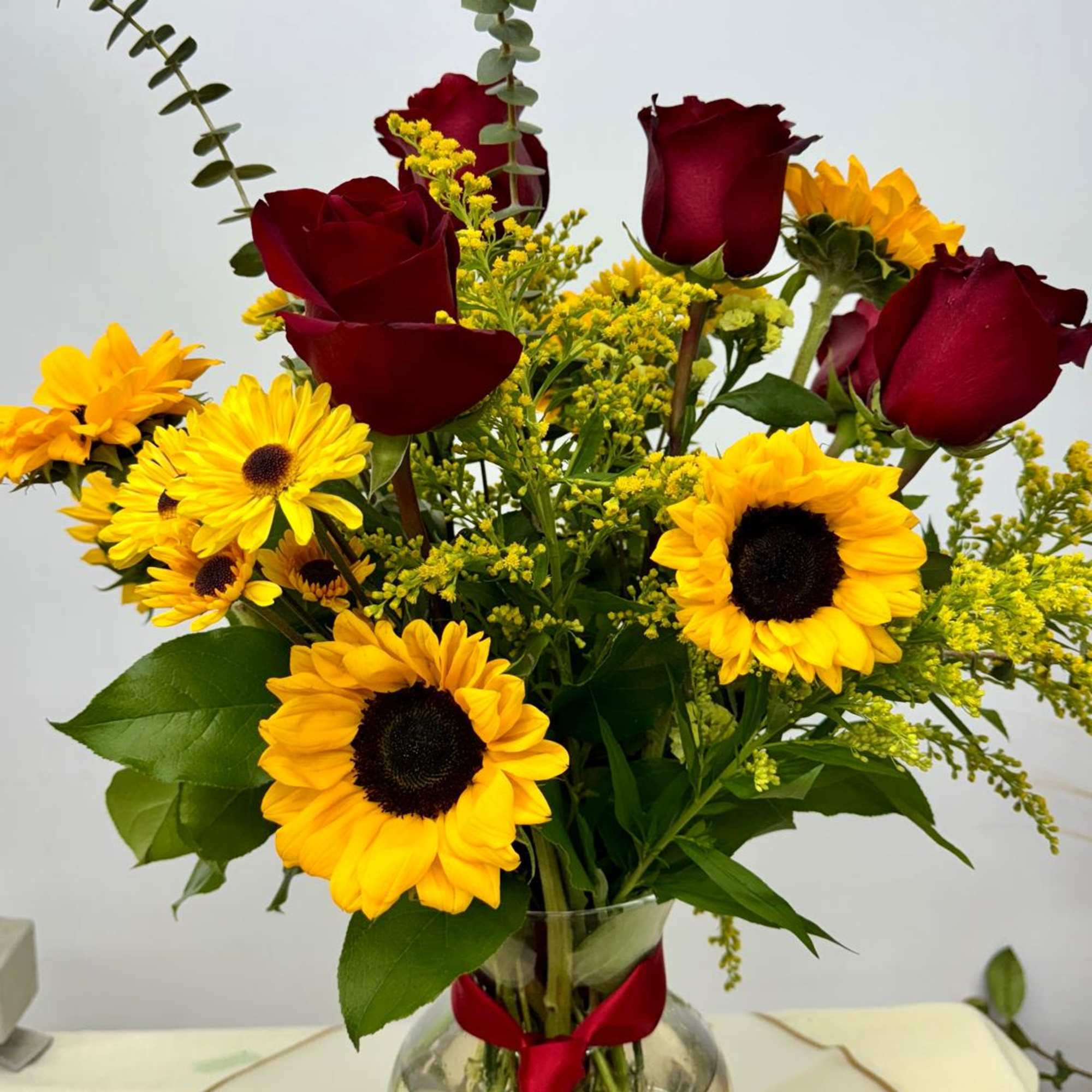 Bouquet of red roses and yellow sunflowers in a glass vase