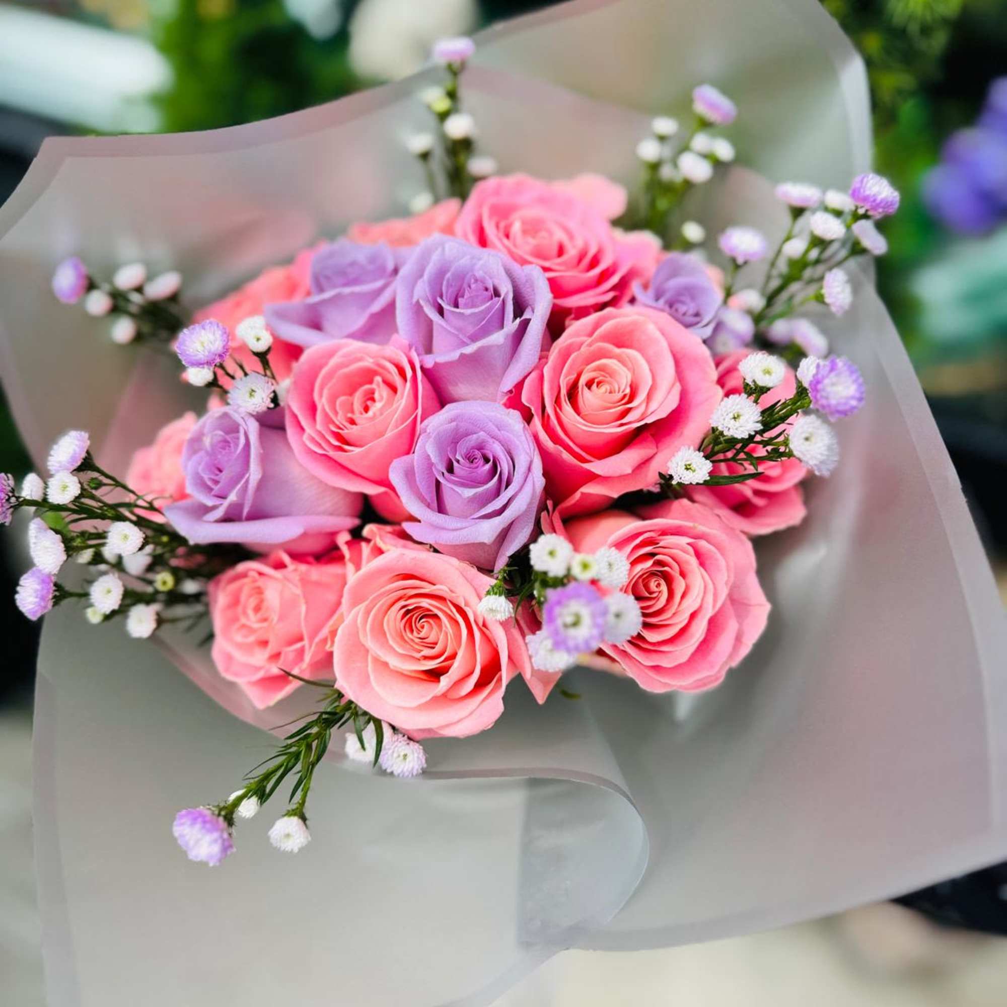 Bouquet of pink and lavender roses wrapped in pale paper