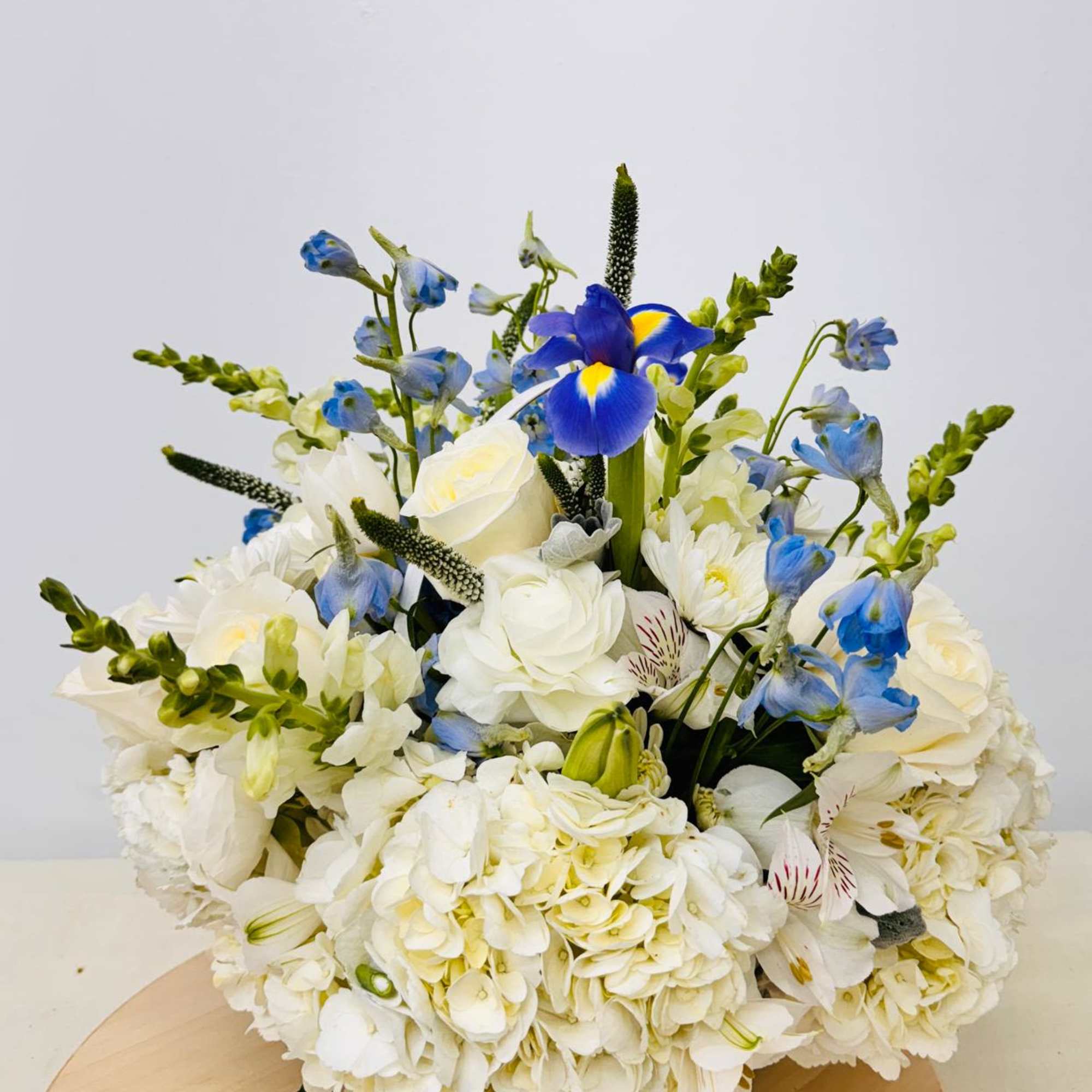 White and blue floral arrangement with roses and iris on a round table