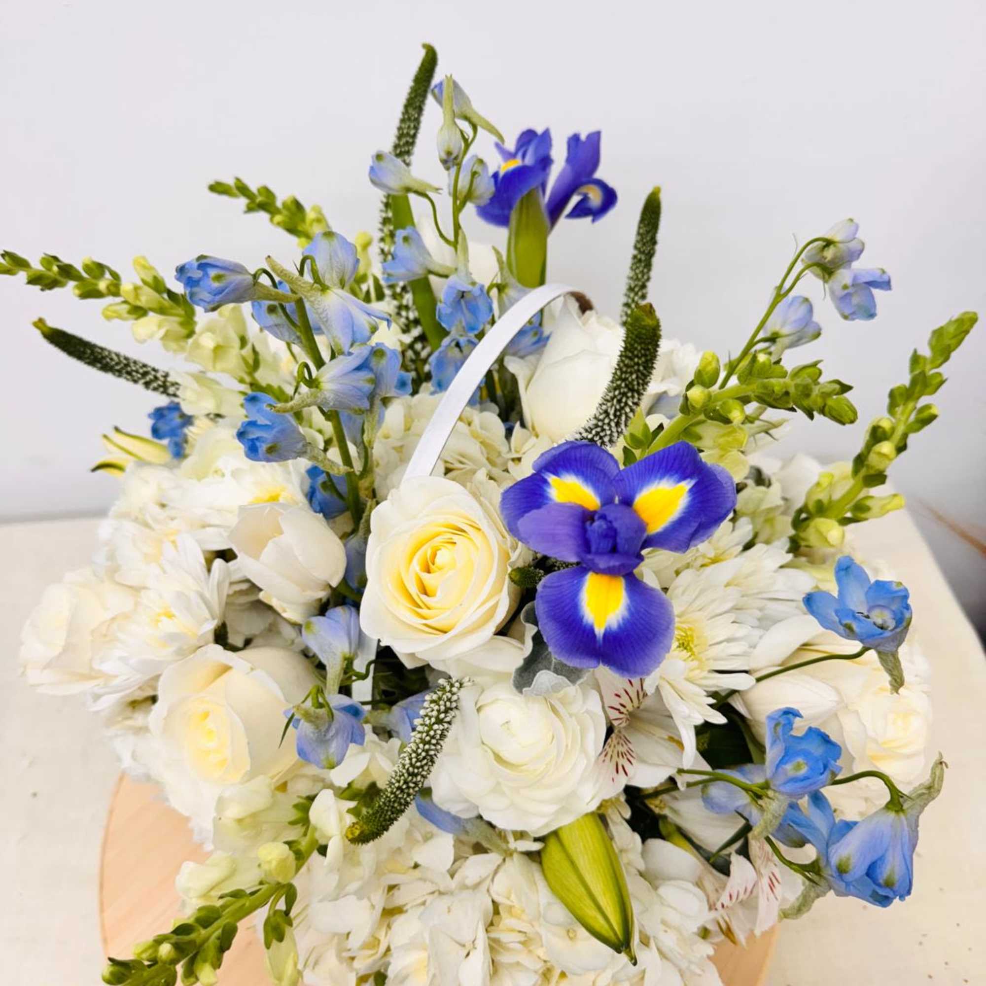 Bouquet of white and blue flowers with a purple iris in a round box