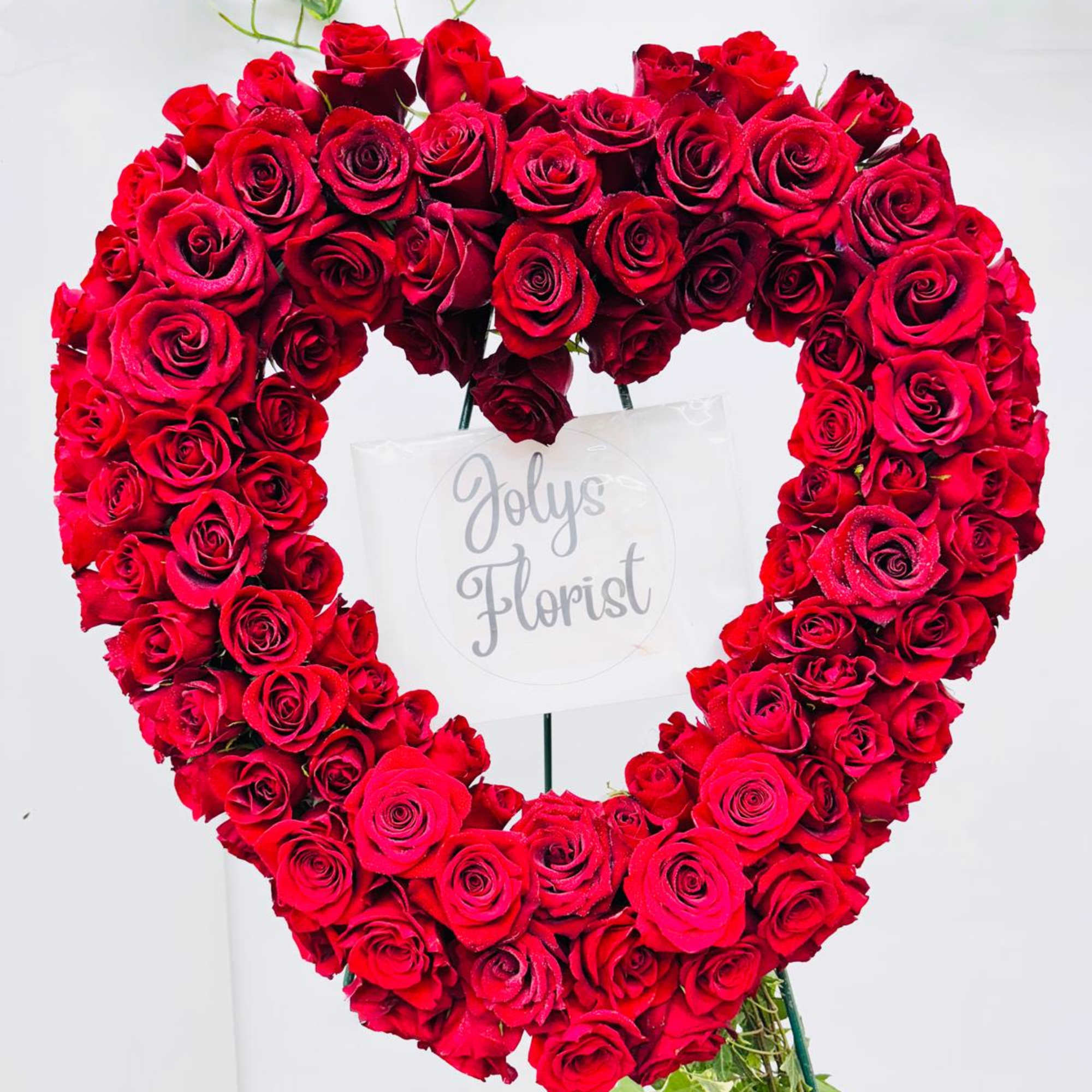 Heart-shaped arrangement of red roses on a stand