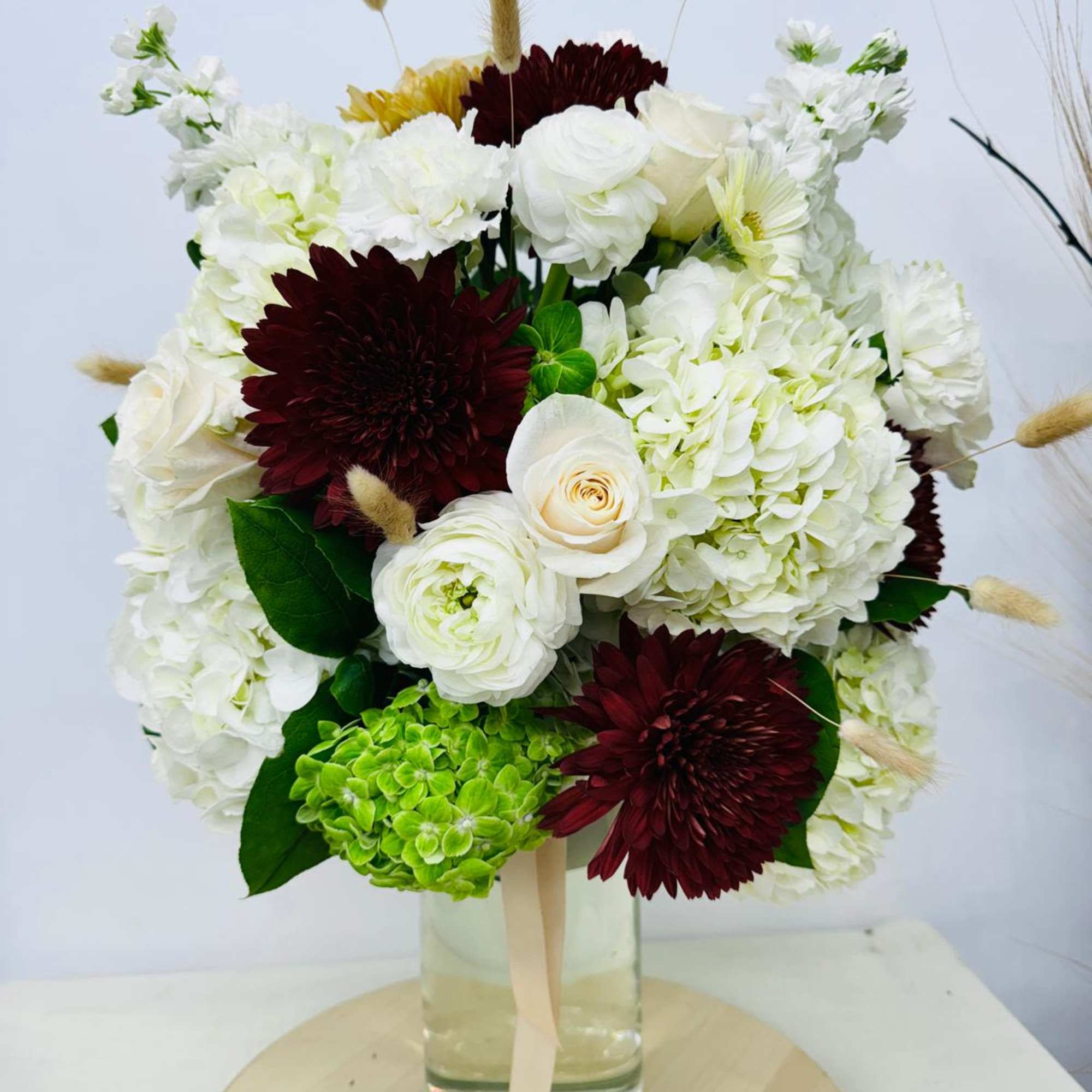 Bouquet of white and burgundy flowers in a glass vase