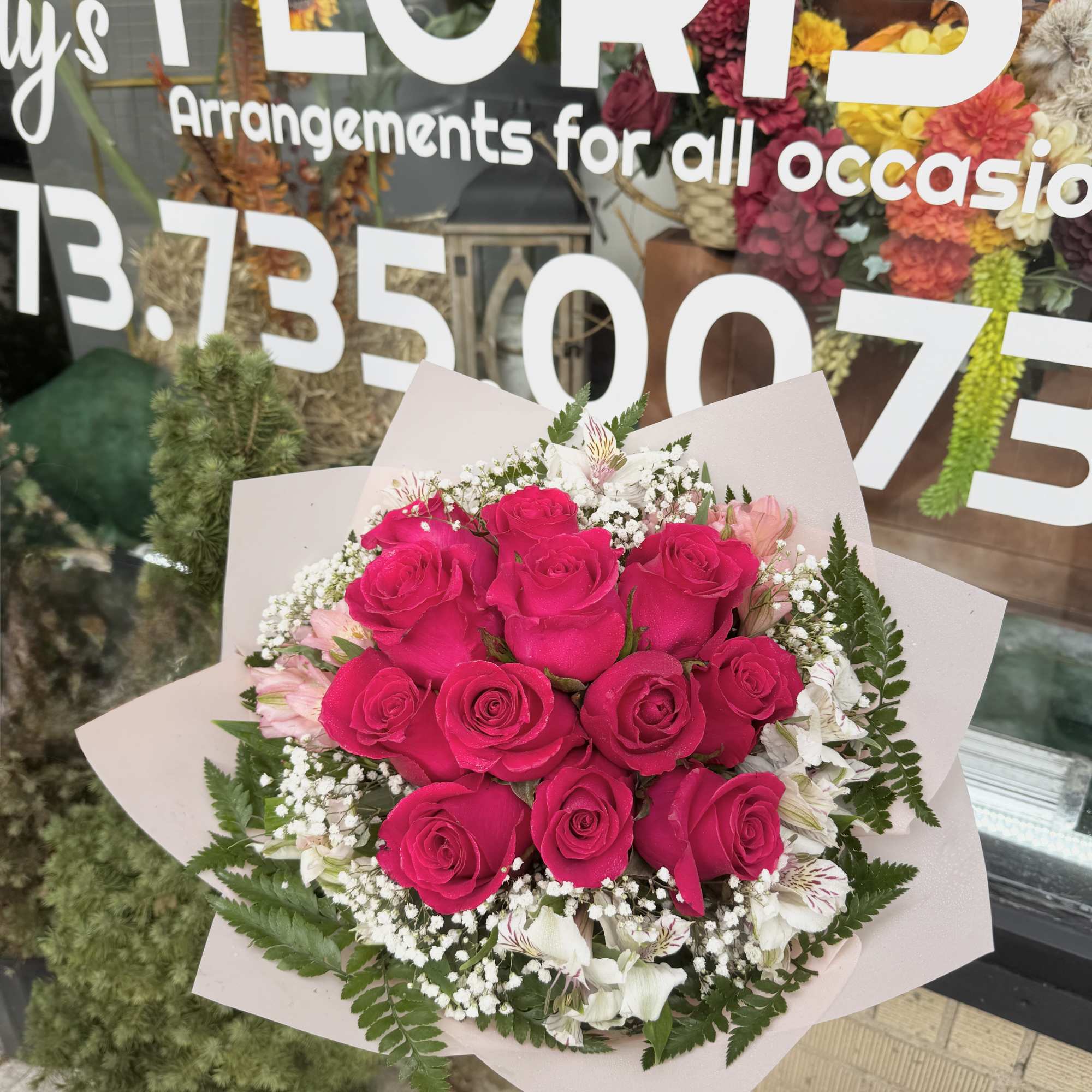 Bouquet of hot pink roses with white filler flowers and pale wrapping