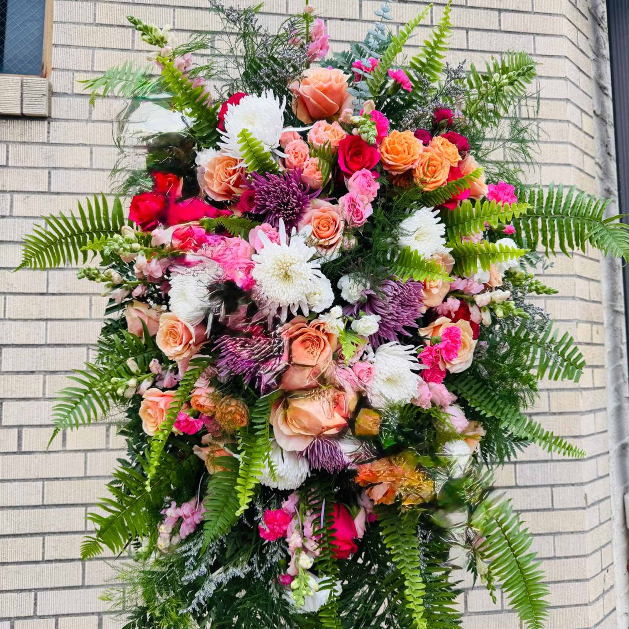 Large standing floral spray with pink, peach, white, and purple flowers